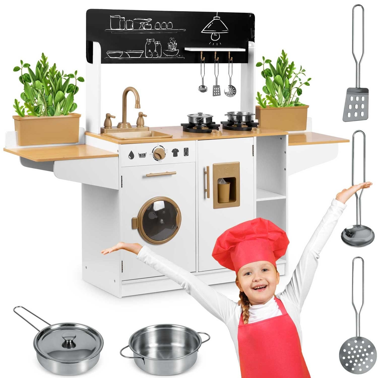 Una niña con atuendo de chef está de pie cerca de una cocina de juguete. Tiene un fregadero, una estufa y una pizarra negra. Se ven ollas, sartenes y utensilios.