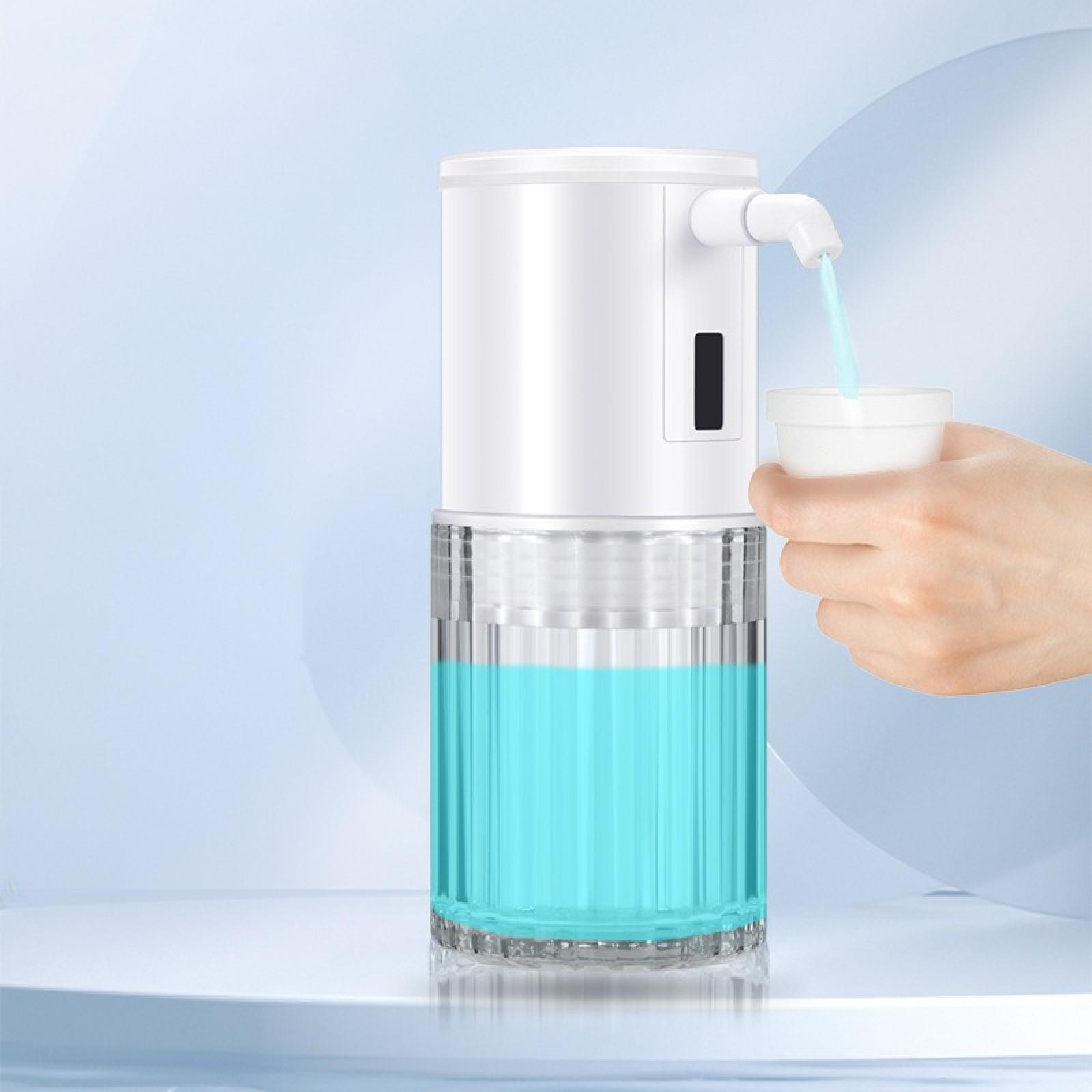 Weißer, automatischer Seifenspender mit blauer Flüssigkeit. Wasser fließt in einen Becher, der von einer Hand gehalten wird.