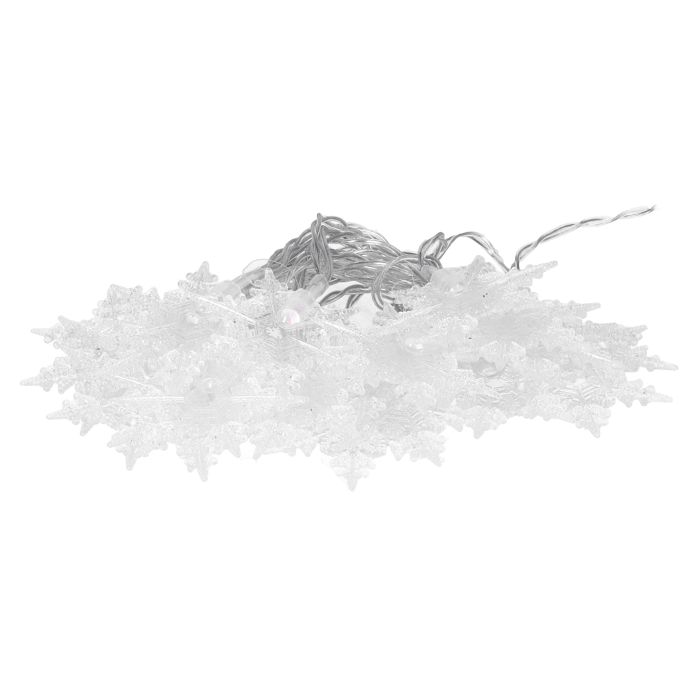 Ein Haufen klarer, schneeförmiger Weihnachtsbeleuchtung. Silberne Drähte verbinden sie. Der Hintergrund ist weiß.