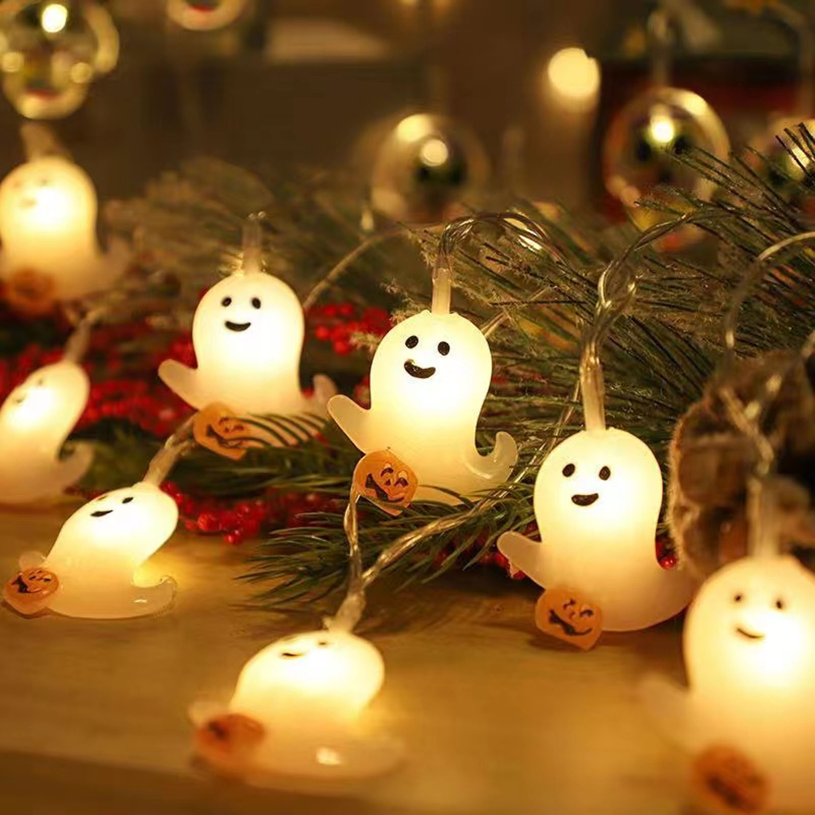 Lichterkette mit leuchtenden weißen Geisterfiguren und kleinen Kürbislaternen, festlich und Halloween-Thema.