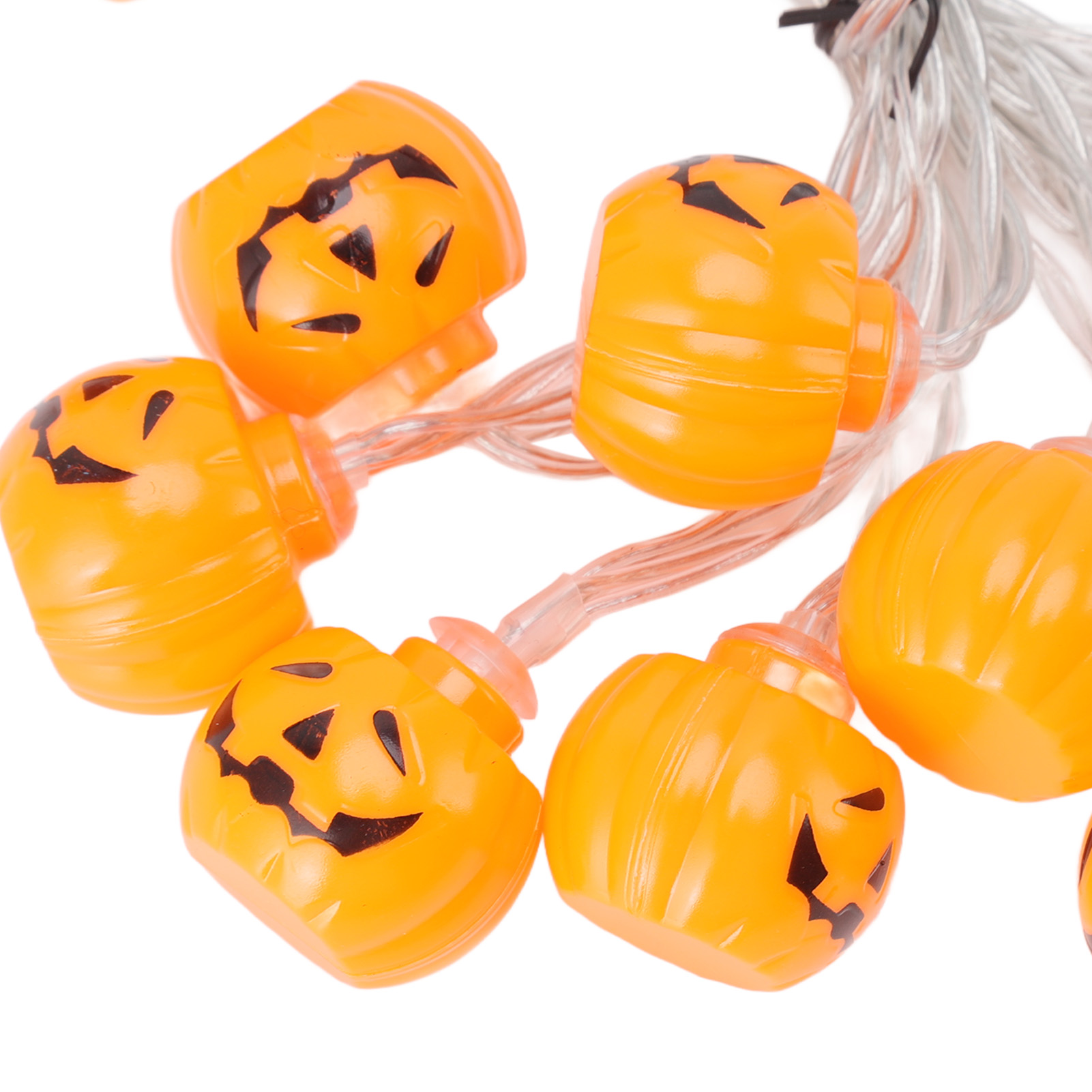 Orangefarbene Kürbislichter mit schwarzen Gesichtern sind auf klaren Drähten aufgereiht, vor weißem Hintergrund.