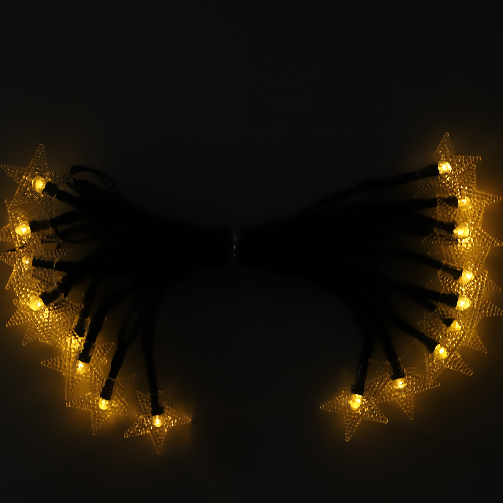 Eine Lichterkette in Sternform, gelb leuchtend, auf schwarzen Drähten vor dunklem Hintergrund.