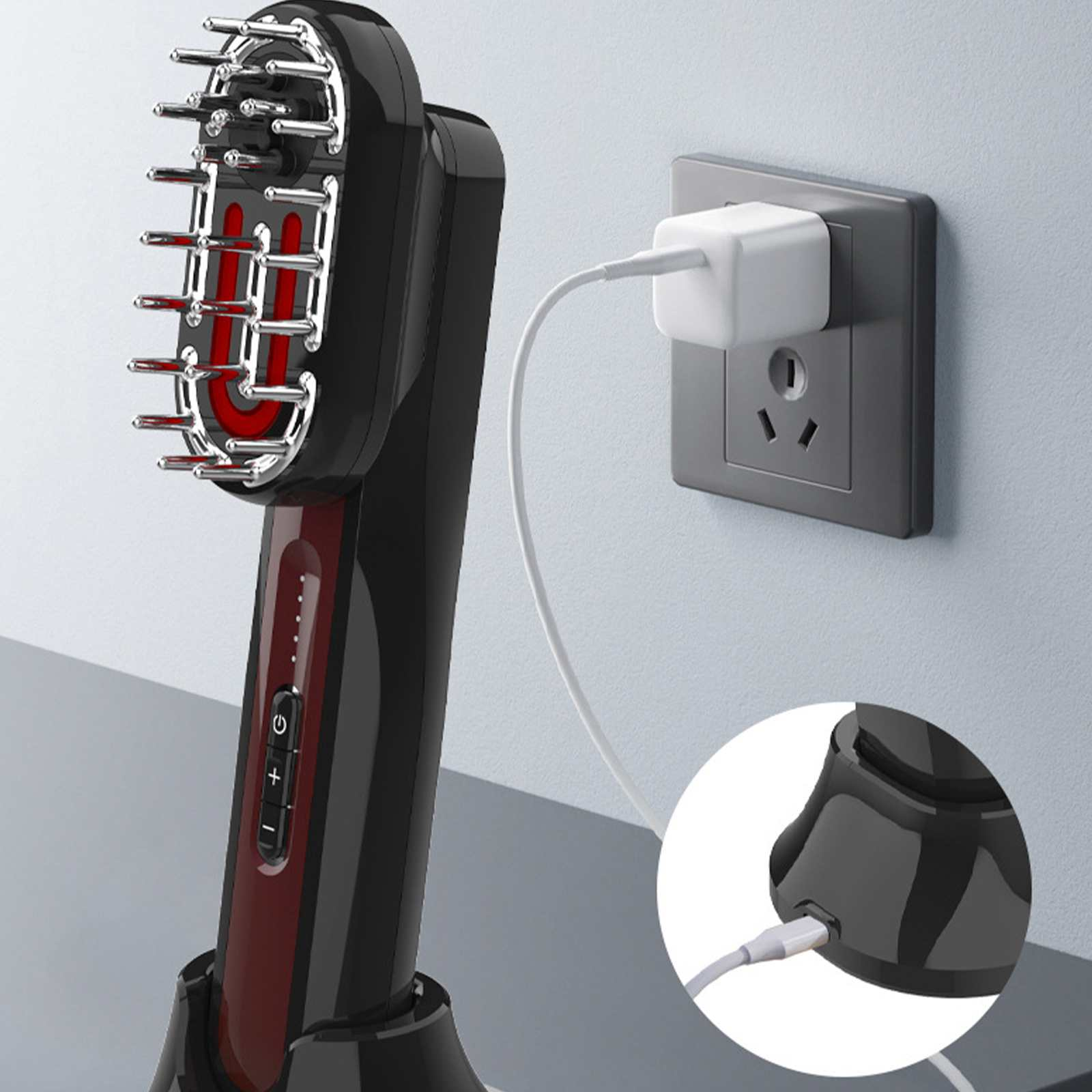 Schwarzes und rotes Haarwuchsgerät an der Wand. Weißes Ladegerät und Kabel. Graue Wand und Oberfläche.