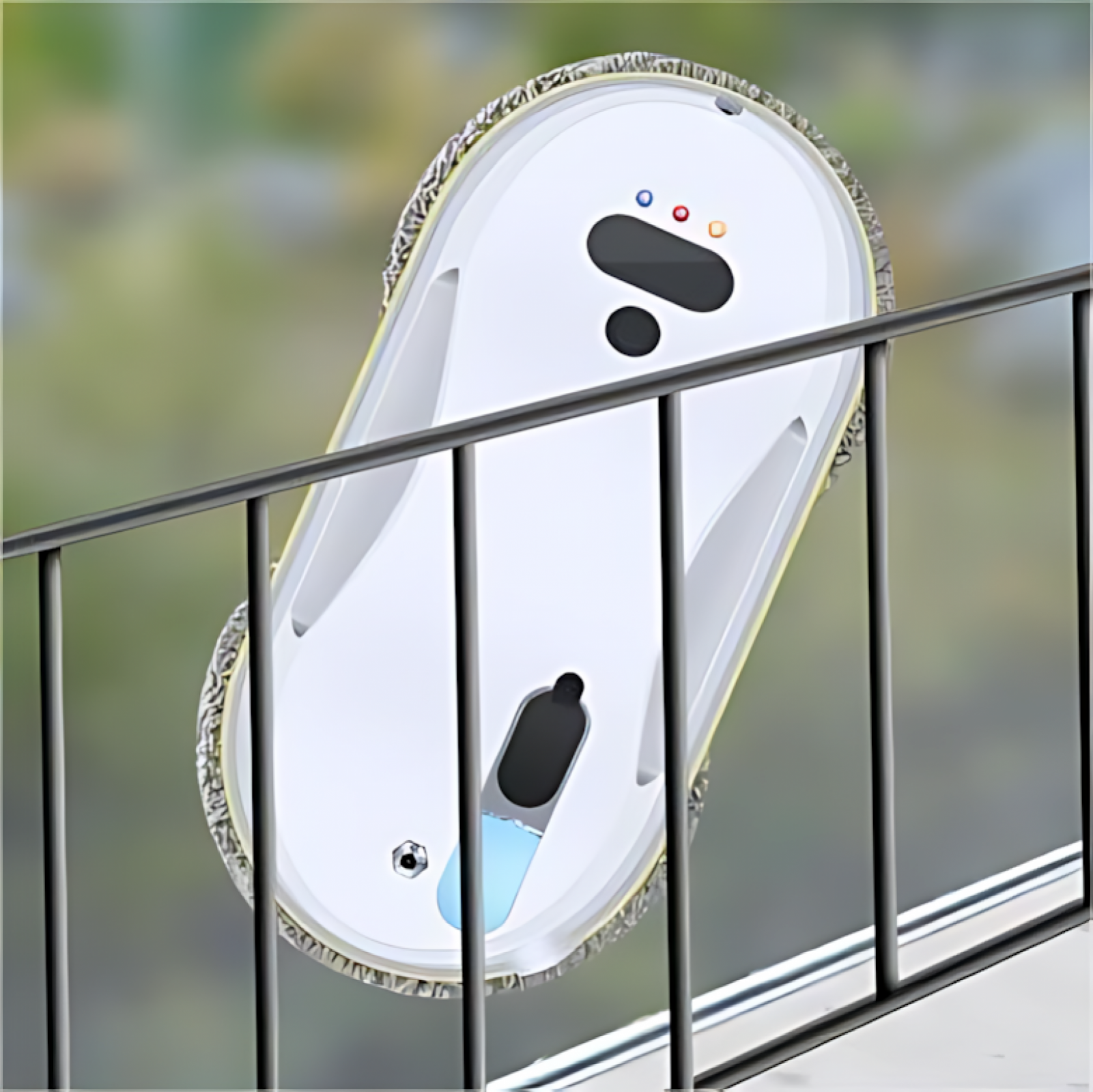 Ein Fensterputzroboter befindet sich auf einem Fenster hinter einem schwarzen Geländer. Der Roboter ist weiß mit einem grauen Putzpad.