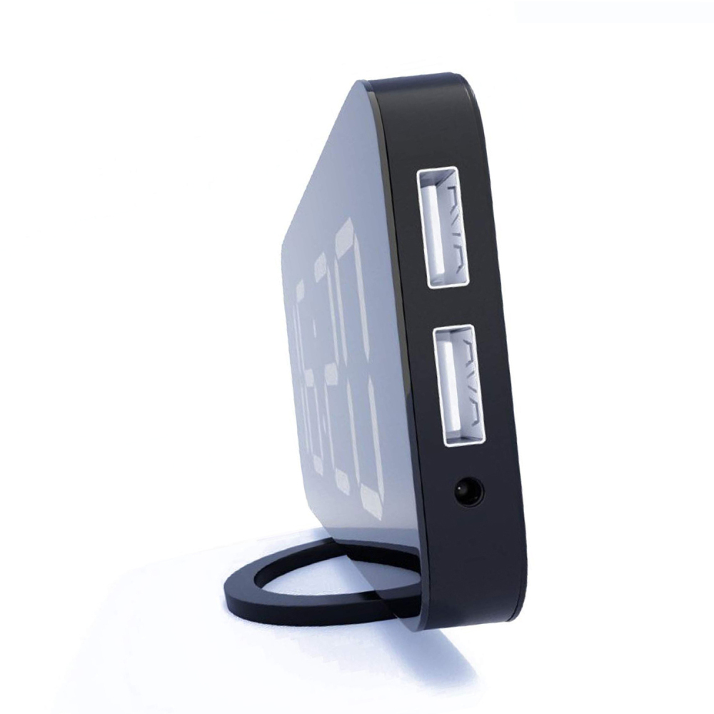 Eine schwarze Digitaluhr mit USB-Anschlüssen, die die Zeit anzeigt. Sie hat einen gebogenen Sockel und steht auf einer weißen Oberfläche.