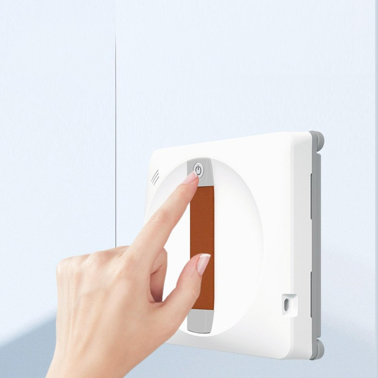 Eine Hand drückt den Einschaltknopf eines weißen Fensterreinigers. Er hat einen braunen Griff und befindet sich an einer blauen Wand.