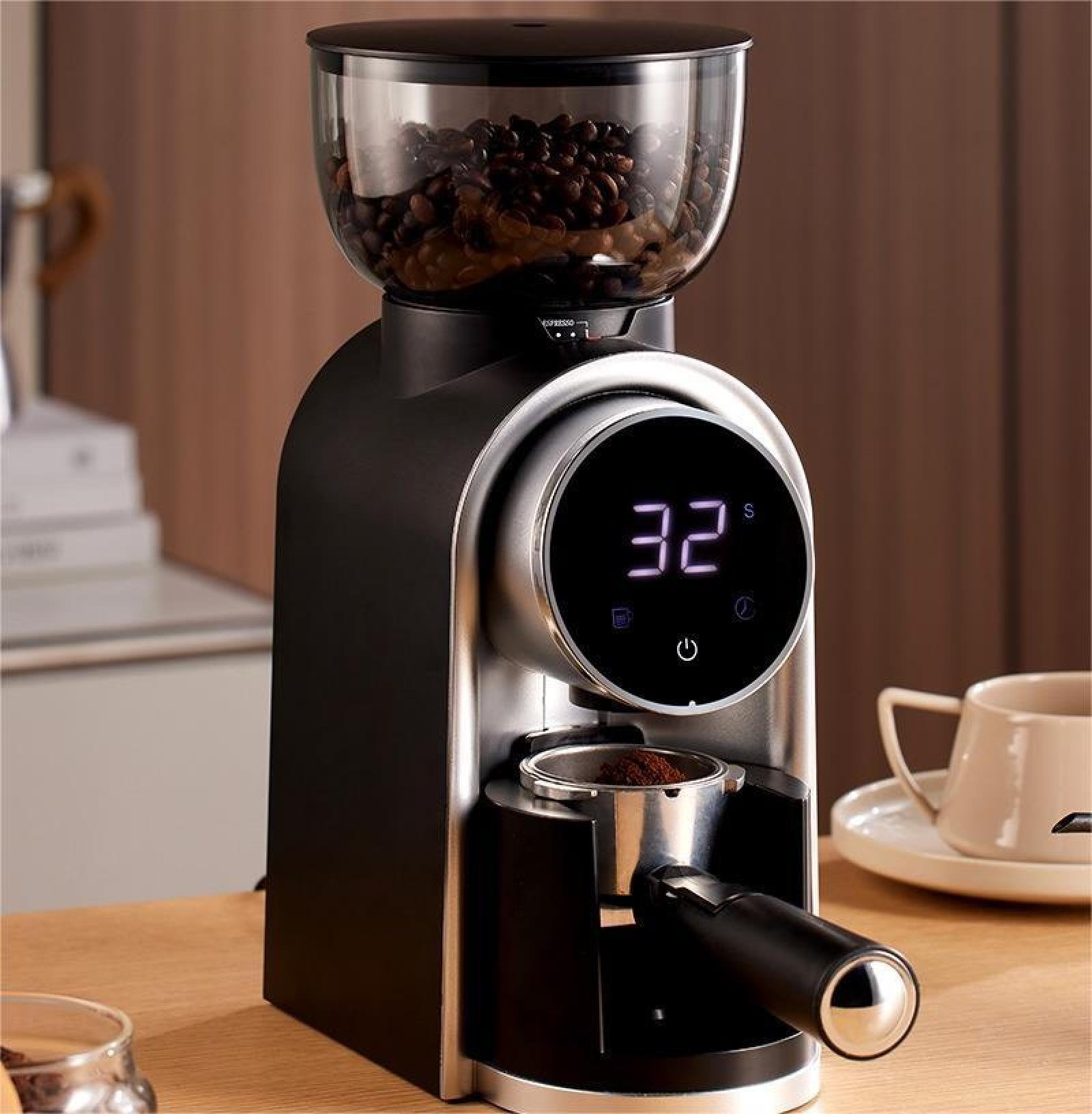 Kaffeemühle mit Bohnen im Trichter, Digitalanzeige und Siebträger. Eine Tasse und Untertasse im Hintergrund.