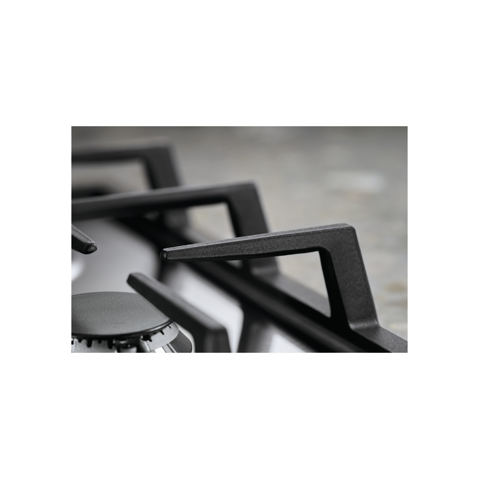 Zbliżenie czarnego palnika kuchenki gazowej z szarym tłem. Skupienie na metalowych wspornikach palnika.