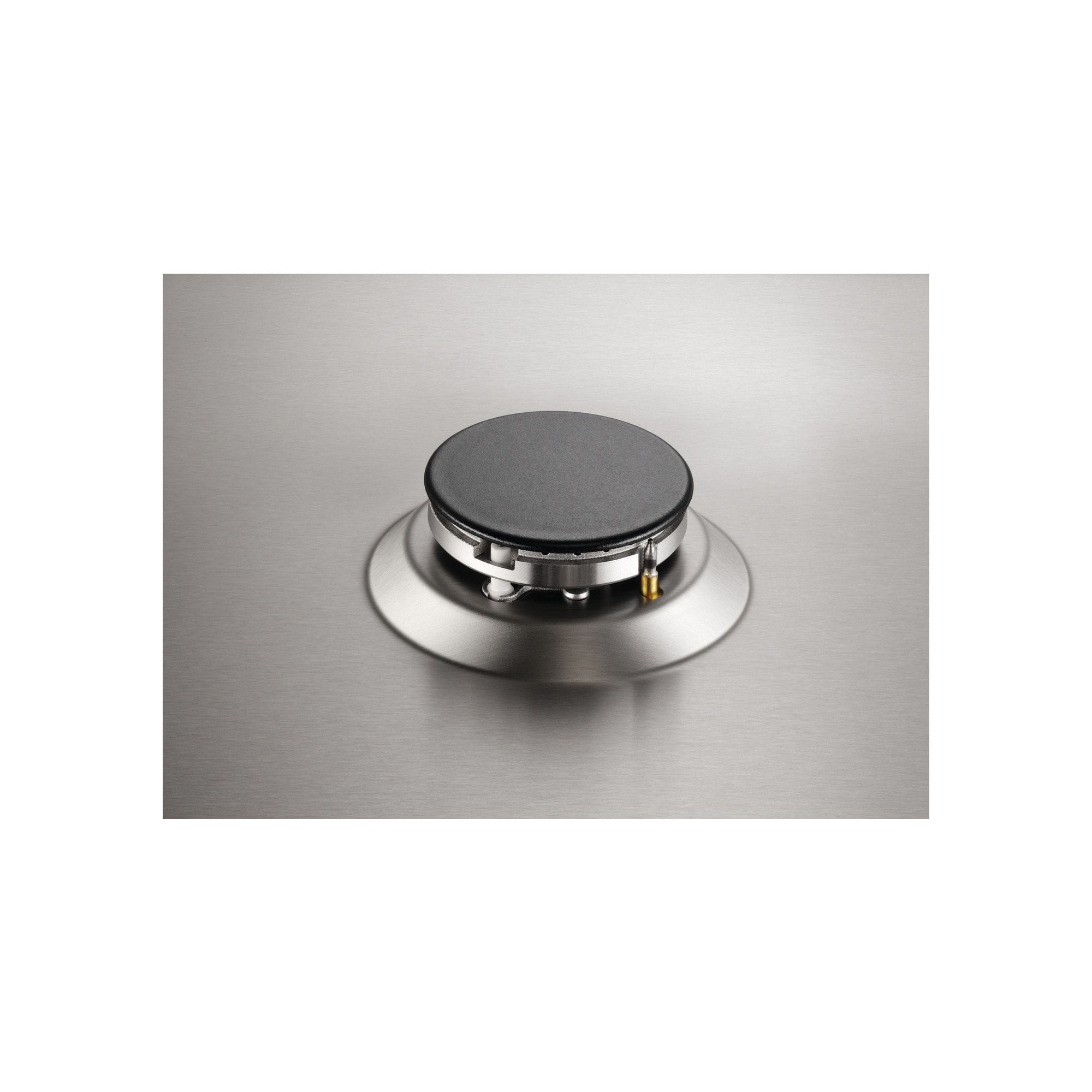 Zbliżenie palnika kuchenki gazowej. Ma czarne centrum ze srebrnym pierścieniem na szczotkowanej metalowej powierzchni.