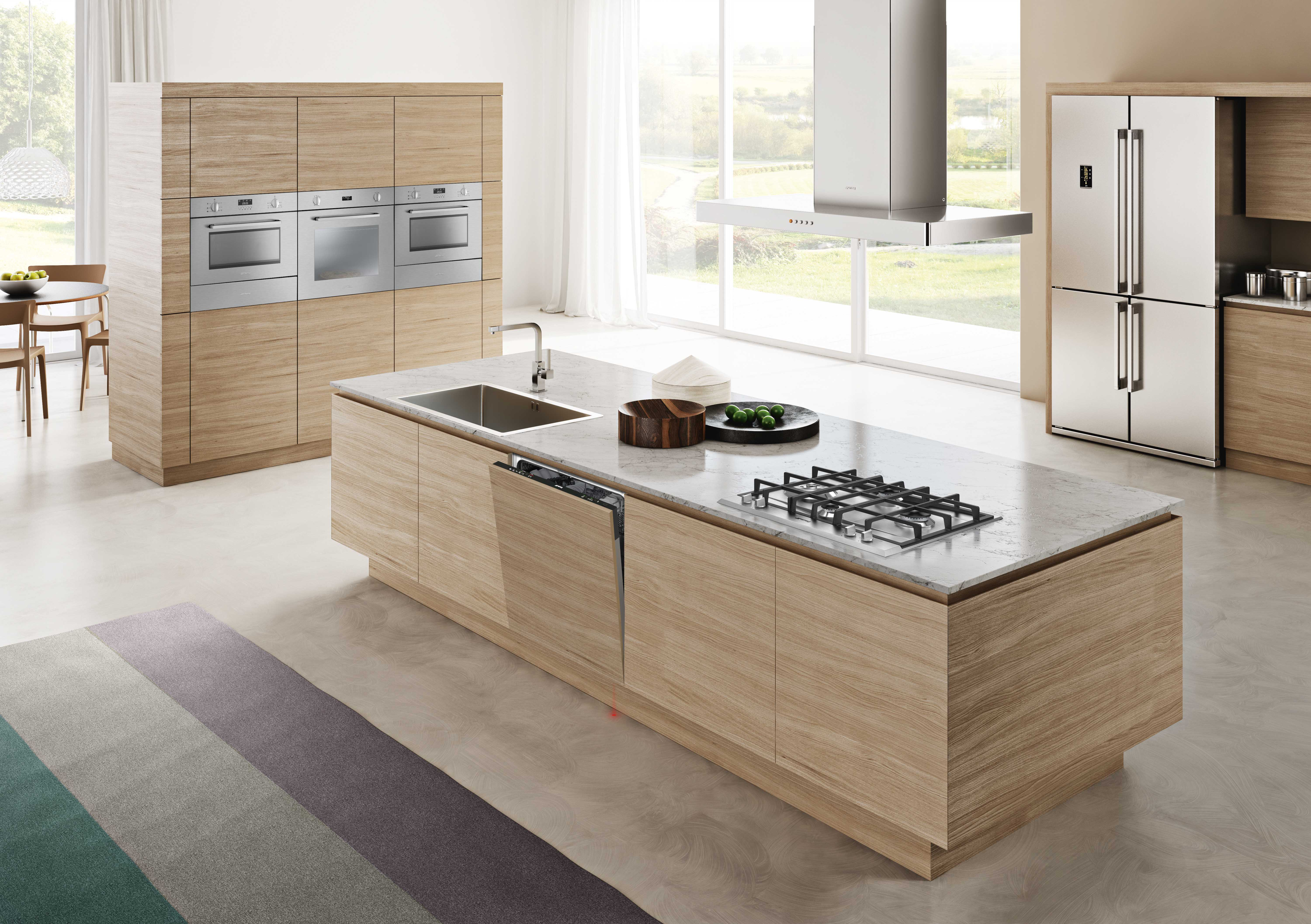 Nowoczesna kuchnia z drewnianymi szafkami, urządzeniami ze stali nierdzewnej, dużą wyspą i widokiem na zewnątrz przez okno.