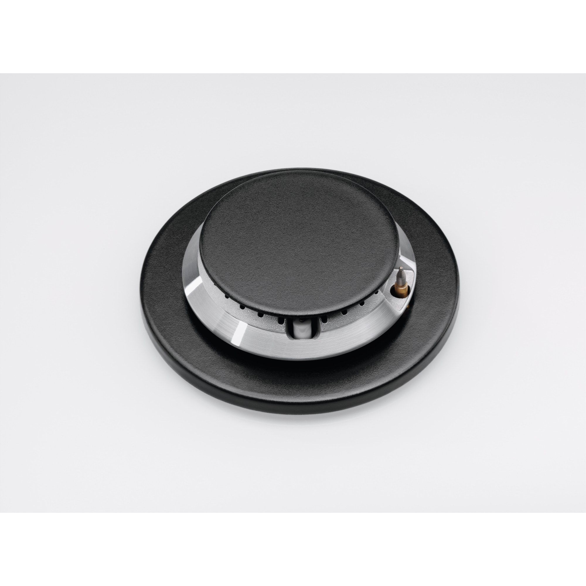 Zbliżenie czarnego palnika kuchenki gazowej na białej powierzchni. Palnik ma metalowy pierścień i czarną nasadkę.