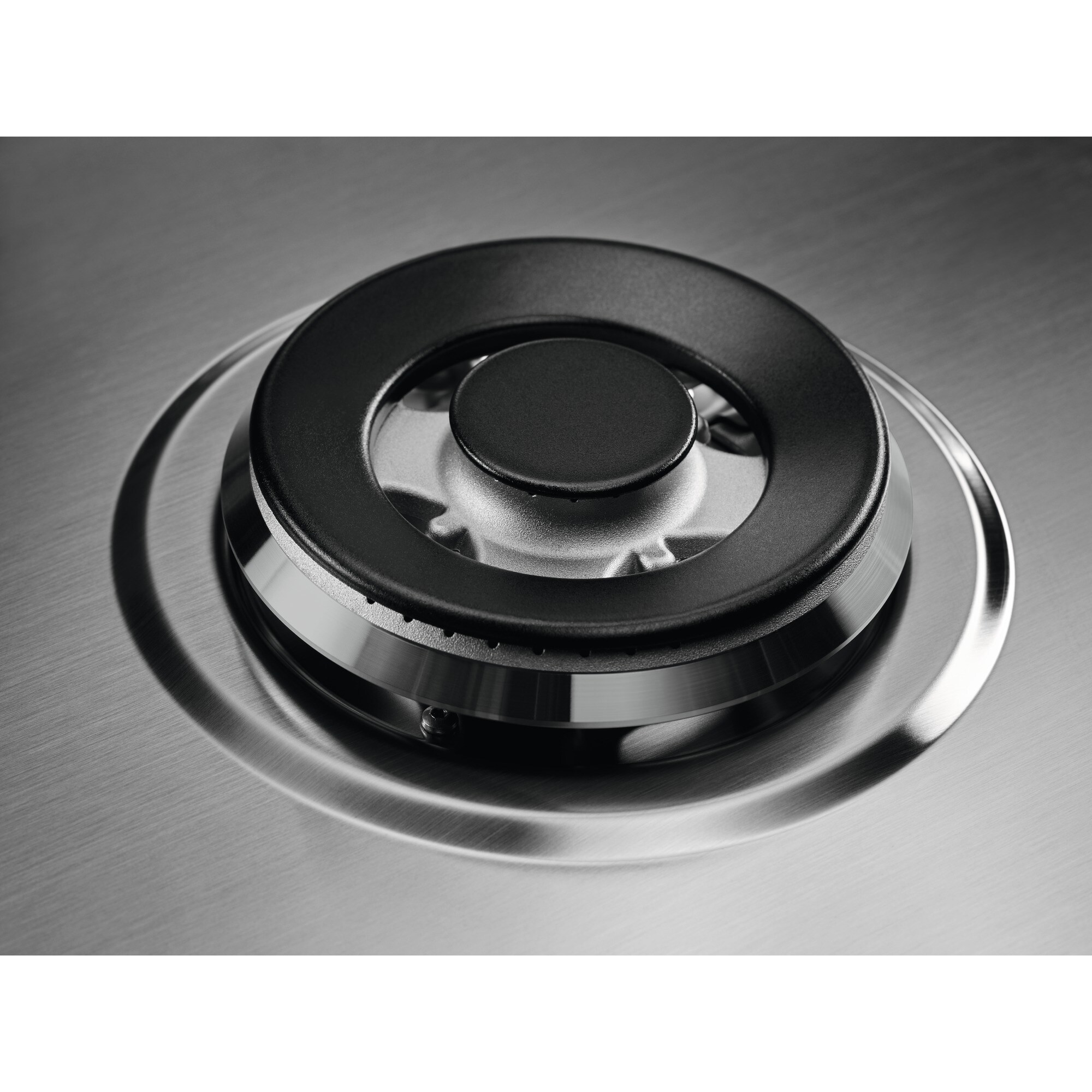 Primo piano di un fornello a gas. Anello nero su superficie in acciaio inox. Il fornello è centrato.