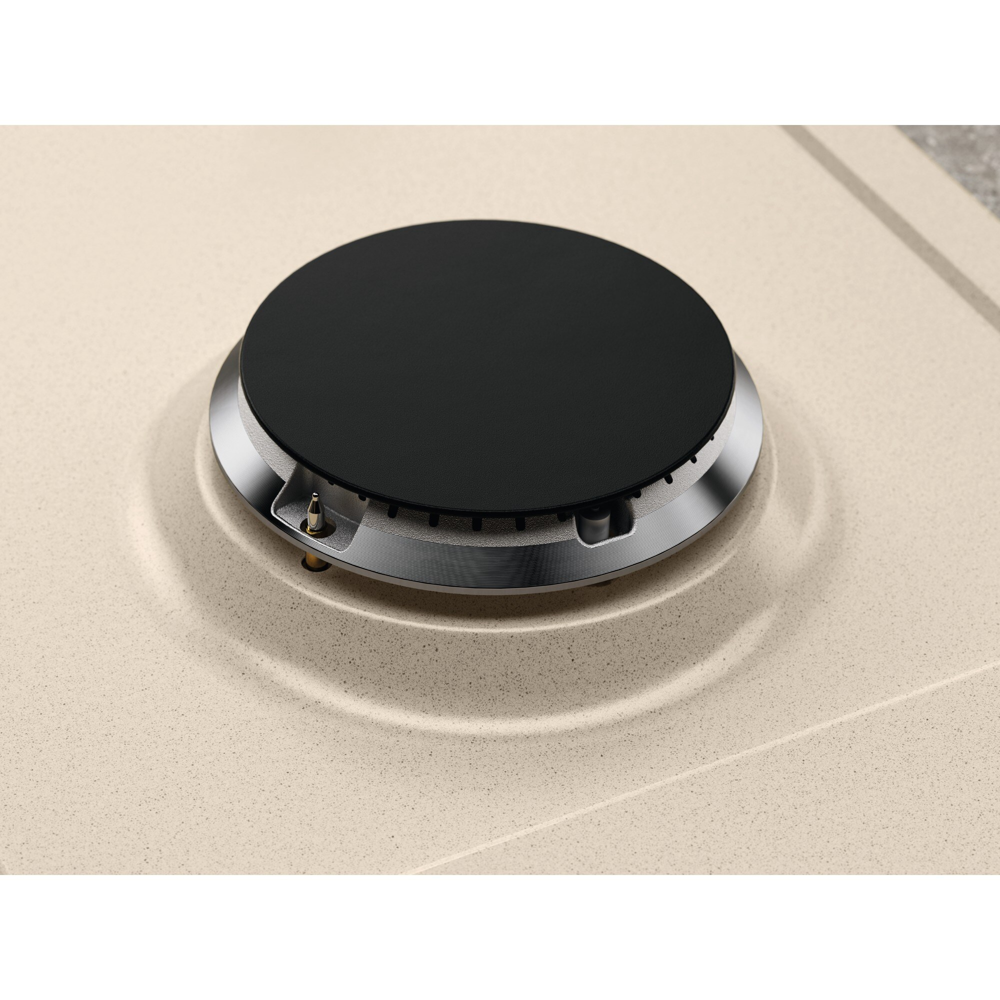 Primer plano de un quemador de estufa negro sobre una encimera beige moteada. El quemador tiene un borde de metal plateado.