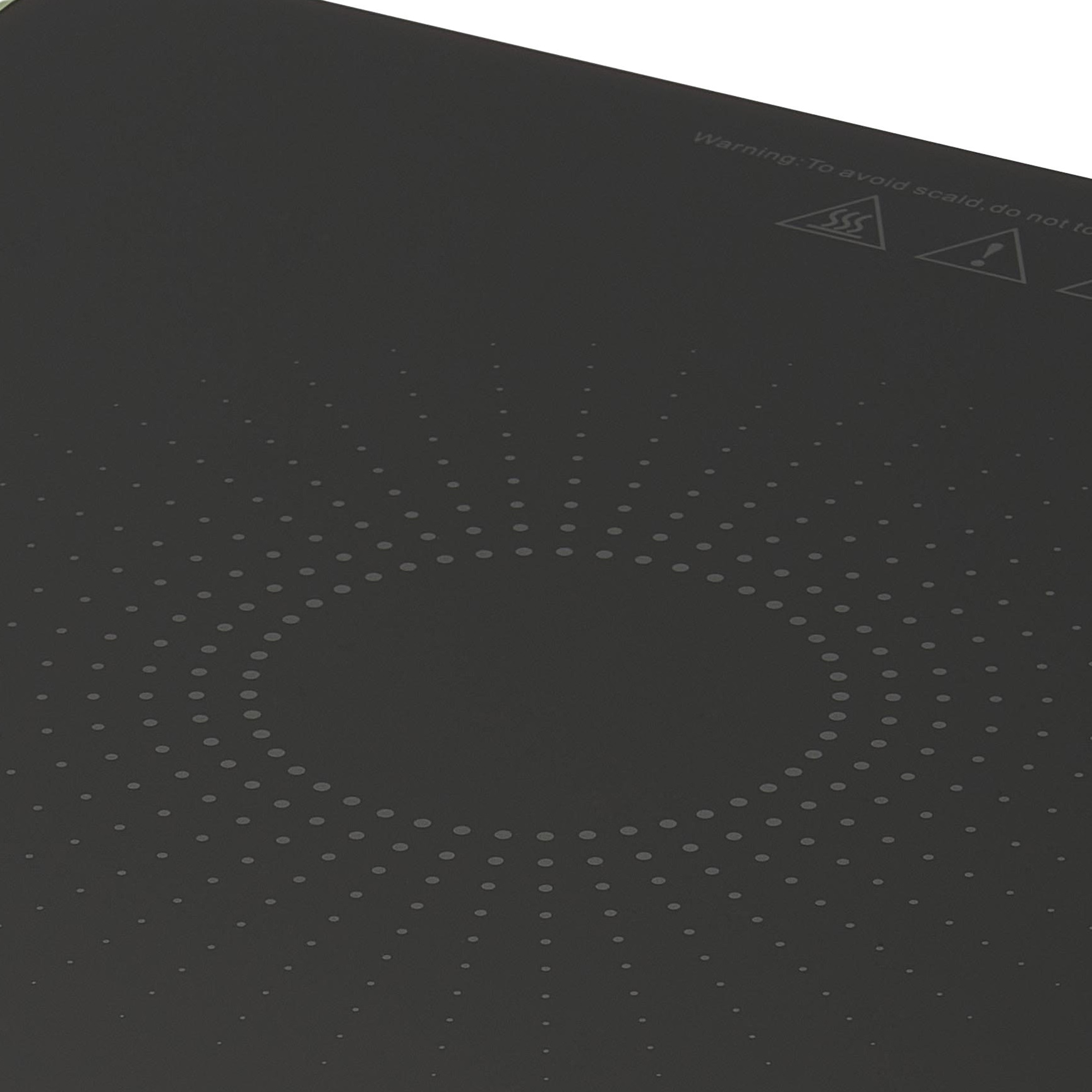 Ciemnoszara powierzchnia z okrągłym wzorem w kropki. Widoczny tekst ostrzegawczy i symbole.