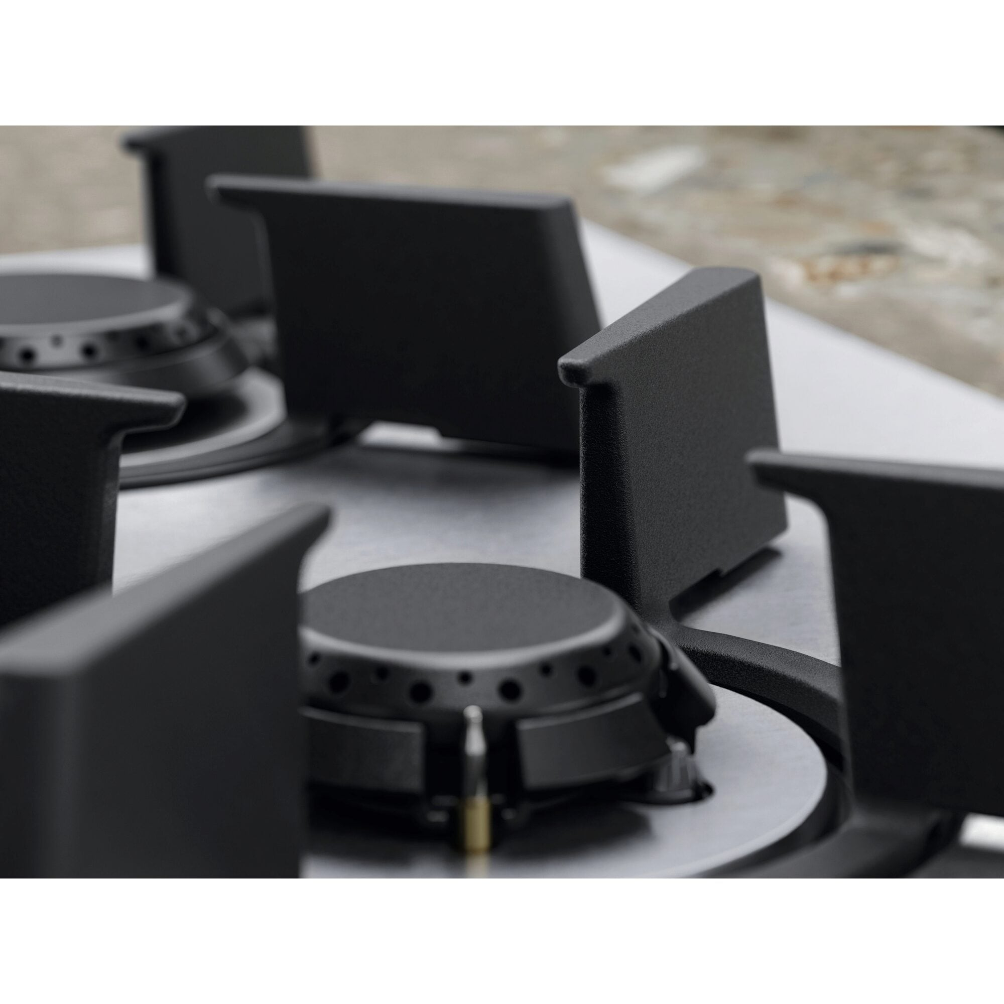 Zbliżenie kuchenki gazowej z czarnymi palnikami i wspornikami na powierzchni ze stali nierdzewnej. Tło jest rozmyte.