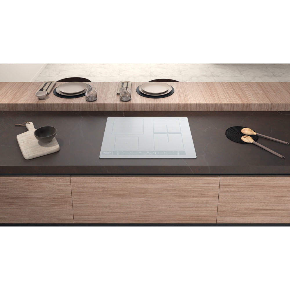 Scena di cucina con piano cottura bianco. Mobili in legno sottostanti, un bancone con piatti e bicchieri sopra.