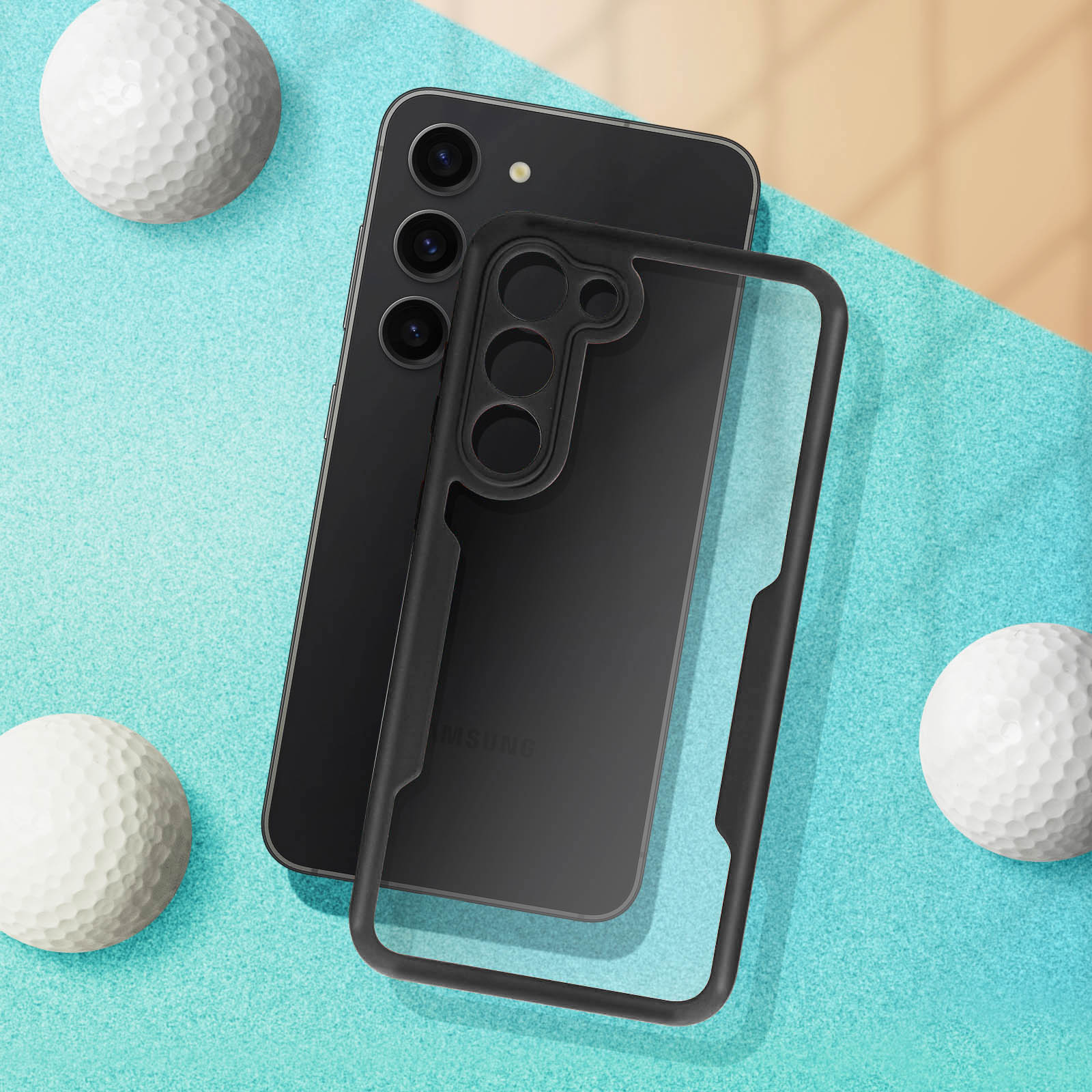 Un telefono nero con una custodia trasparente, tre palline da golf, su una superficie turchese e beige.