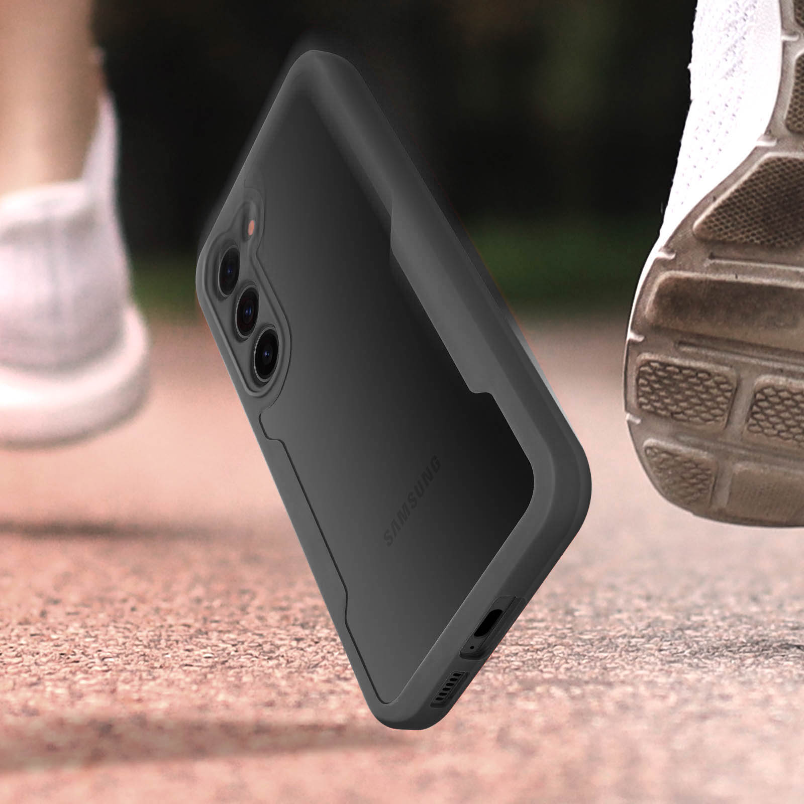 Custodia nera per telefono Samsung a mezz'aria, con piedi e scarpa sfocati sullo sfondo. Custodia con ritagli per fotocamera e logo Samsung.