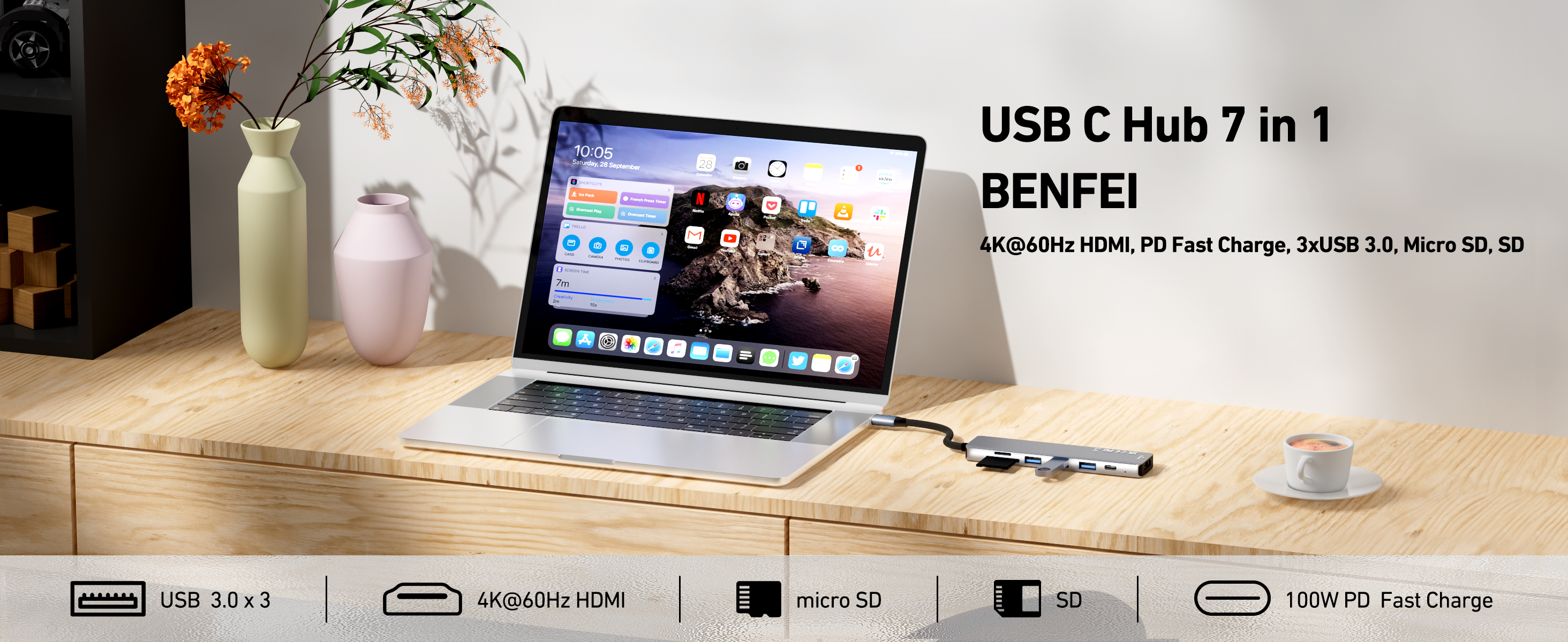Ein Laptop mit USB-C-Hub, Blumen in Vasen und eine Kaffeetasse. Der Laptop zeigt die Uhrzeit und App-Symbole.