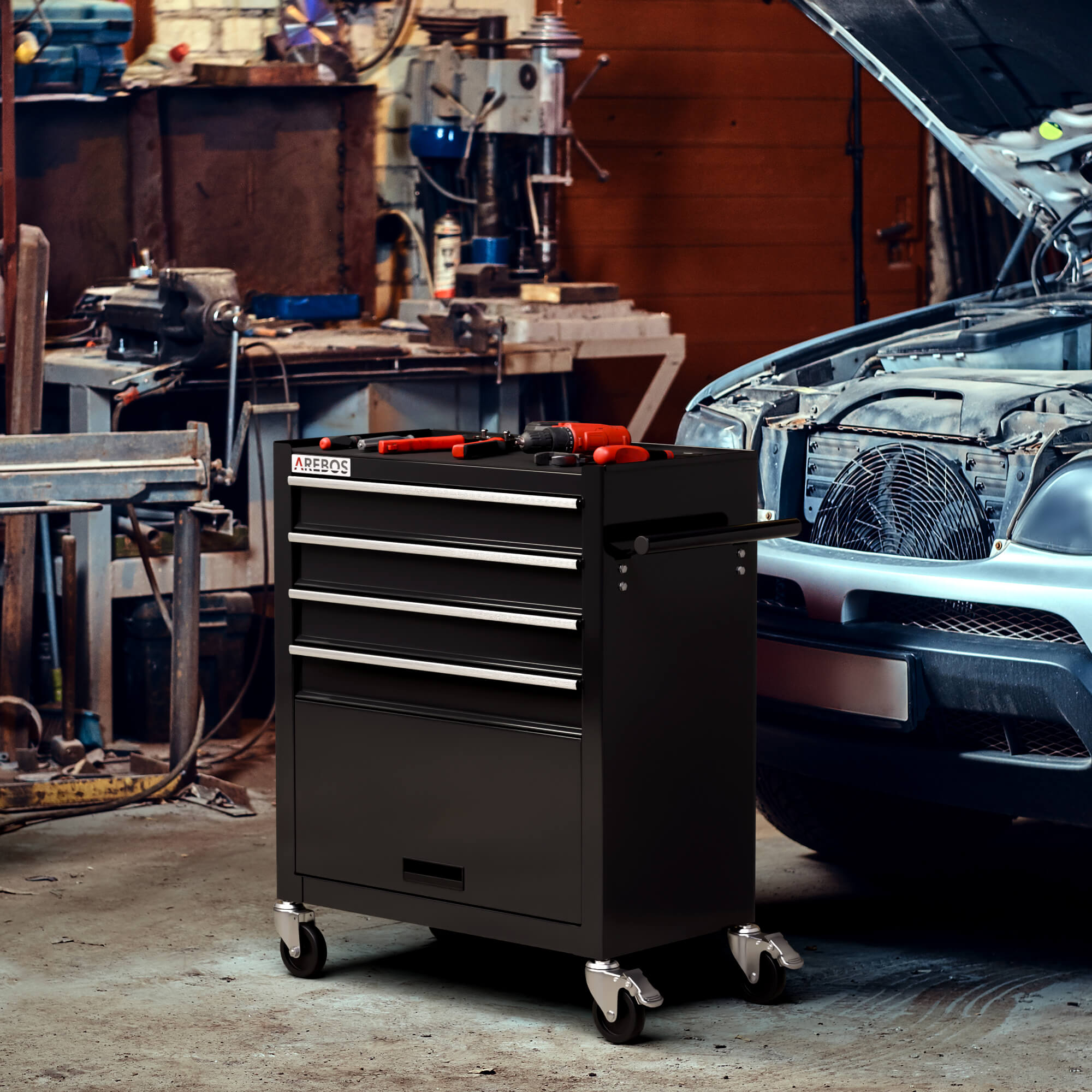 Armoire à outils noire dans un atelier. Outils au-dessus et une voiture avec capot ouvert en arrière-plan.