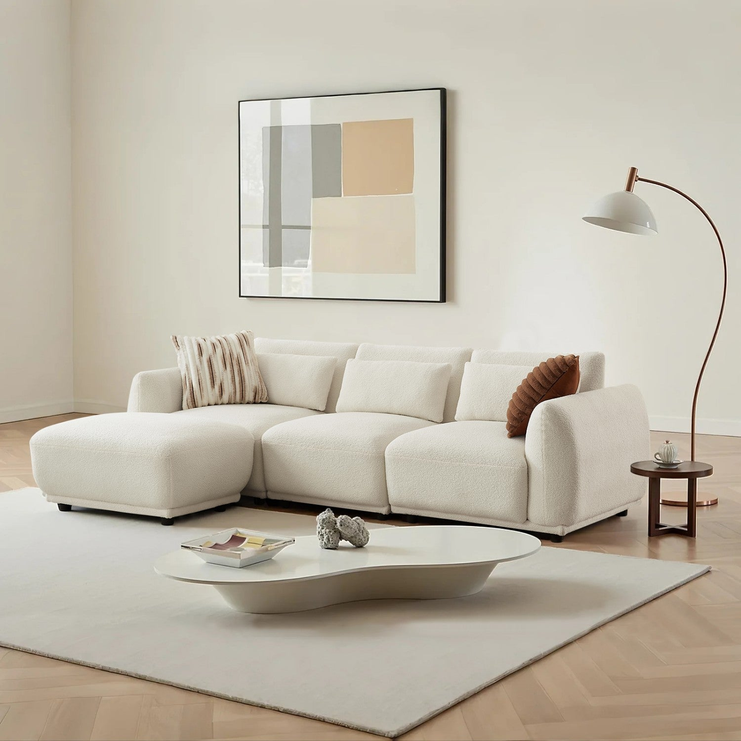 Un soggiorno moderno con divano bianco, tappeto bianco, tavolino e opera d'arte incorniciata sulla parete.