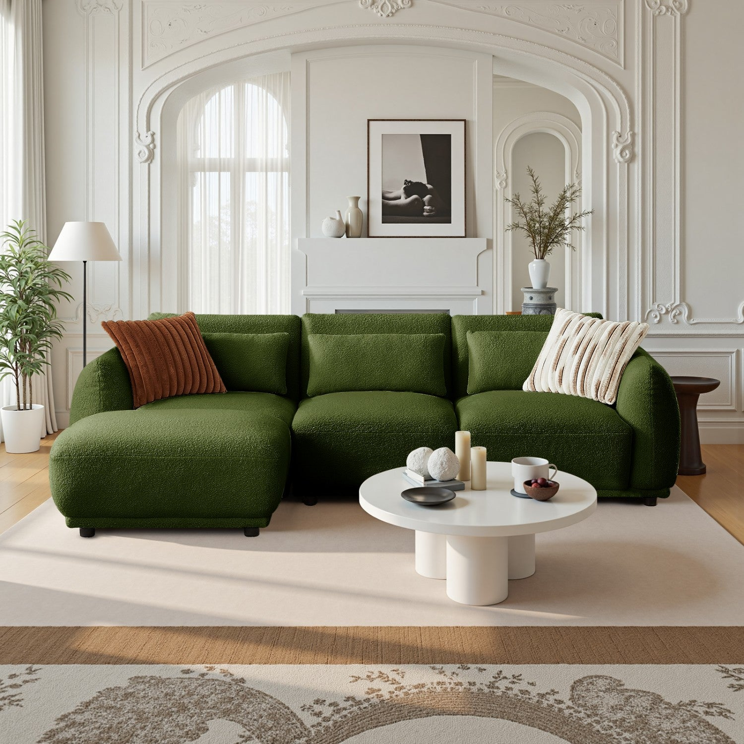 Un sofá verde con almohadas marrones y a rayas está en una habitación con paredes blancas, una alfombra, una mesa de centro y un cuadro enmarcado.