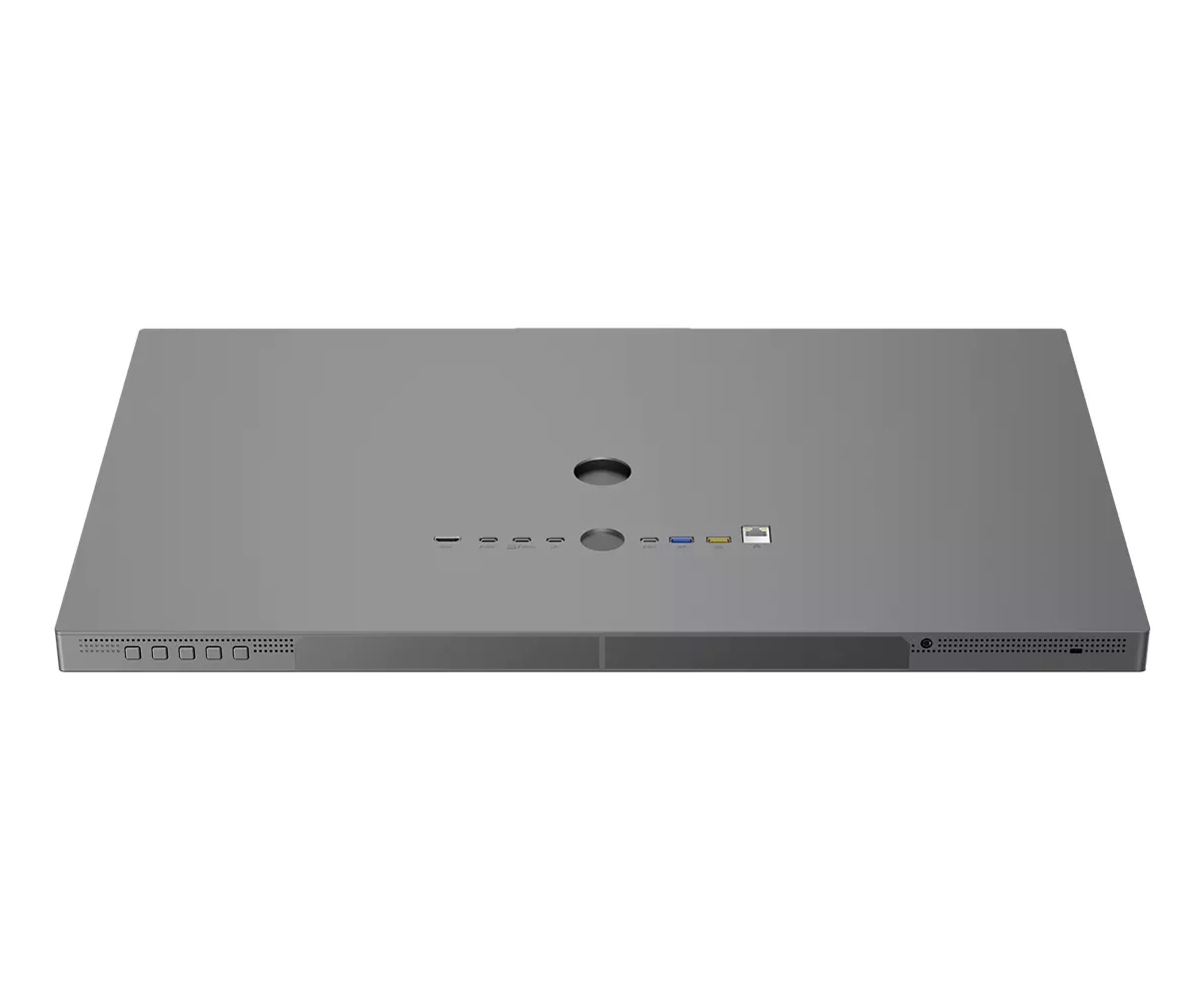 Szare prostokątne urządzenie, prawdopodobnie komputer all-in-one, z różnymi portami i otworami wzdłuż krawędzi.