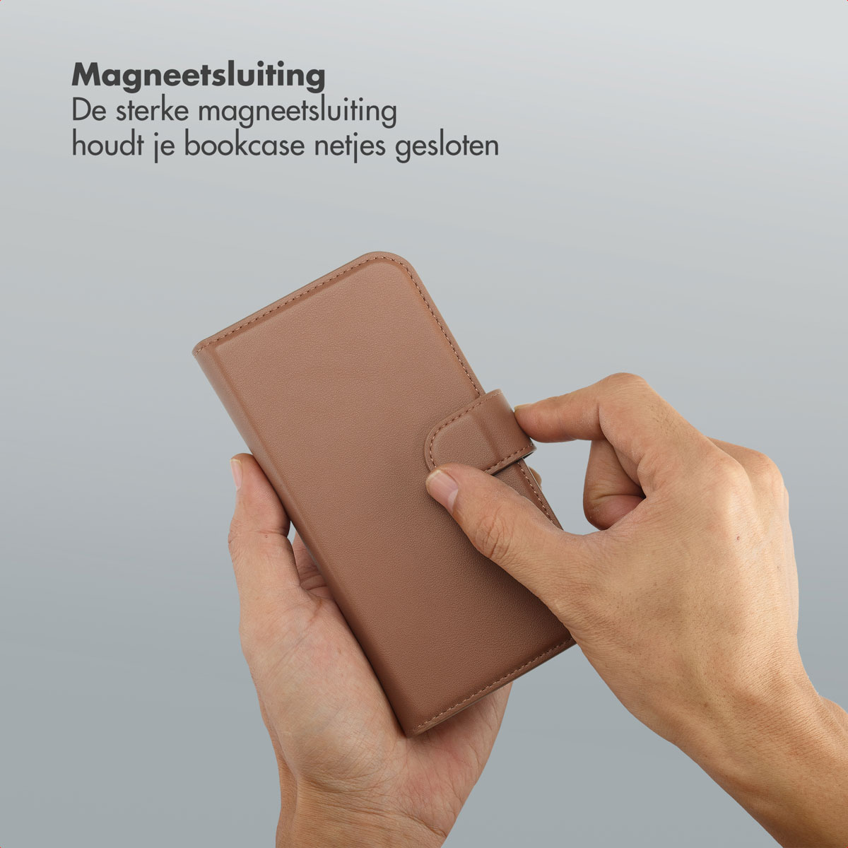Mains tenant un étui de téléphone marron. L'étui est fermé par une fermeture magnétique. Le fond est gris clair.