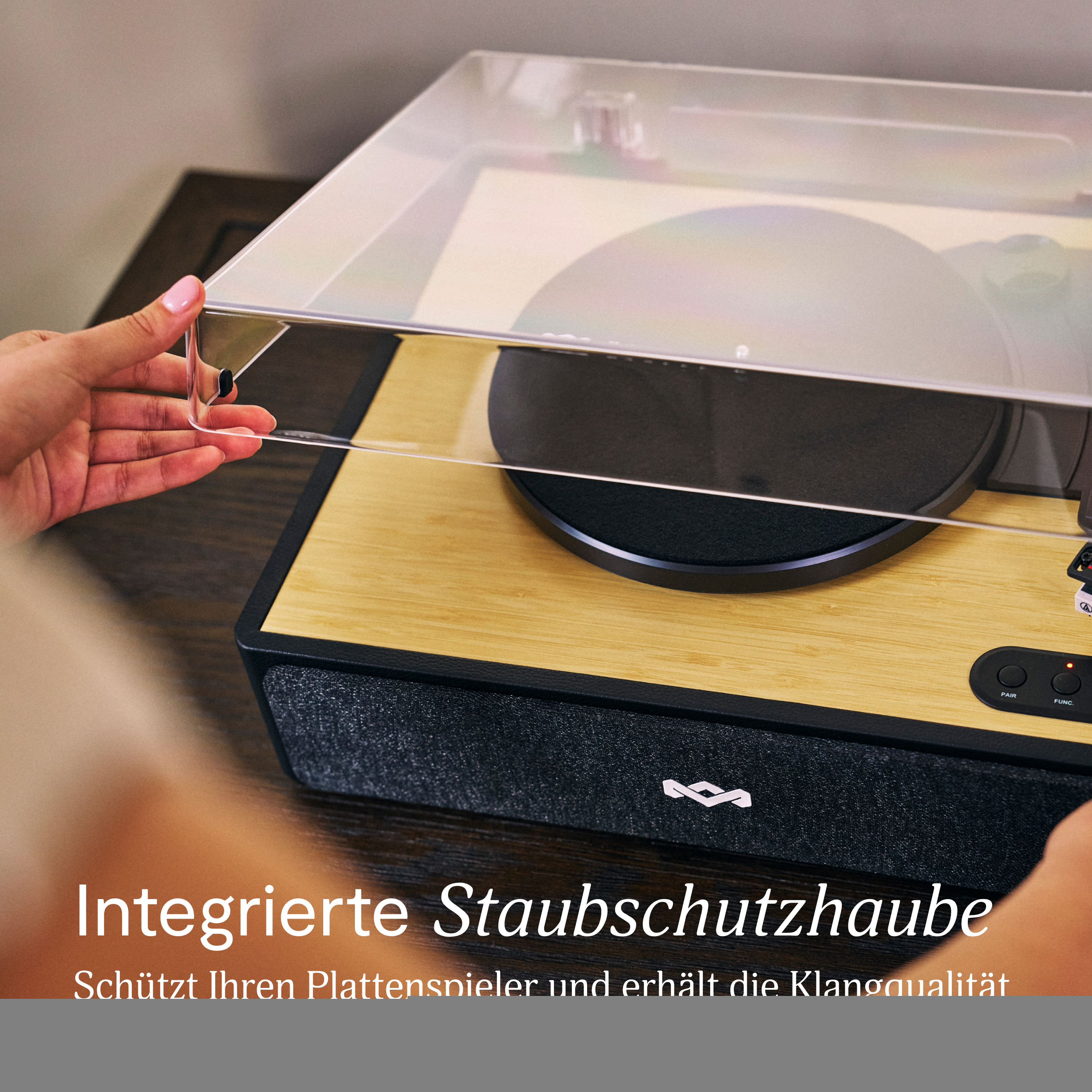 Mains soulevant un couvercle transparent sur une platine. La platine est sur du bois. Texte en bas.