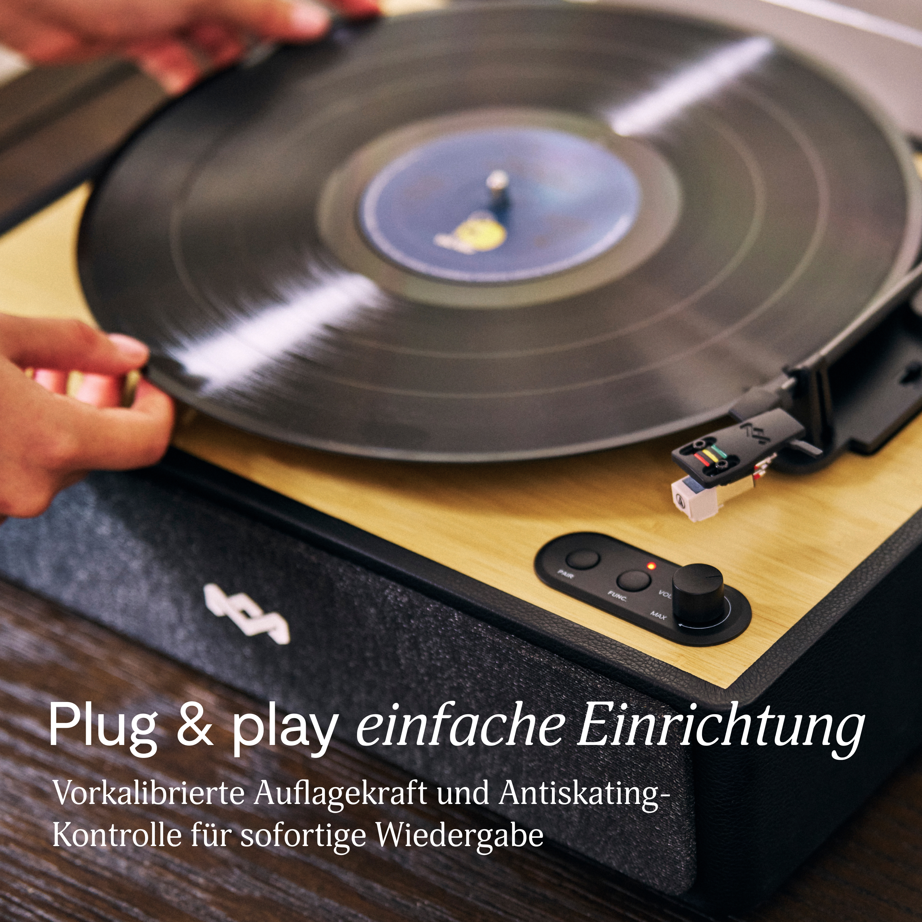 Une personne place un vinyle sur une platine. Le lecteur a des tons noirs et bois avec des boutons et un bouton de volume.