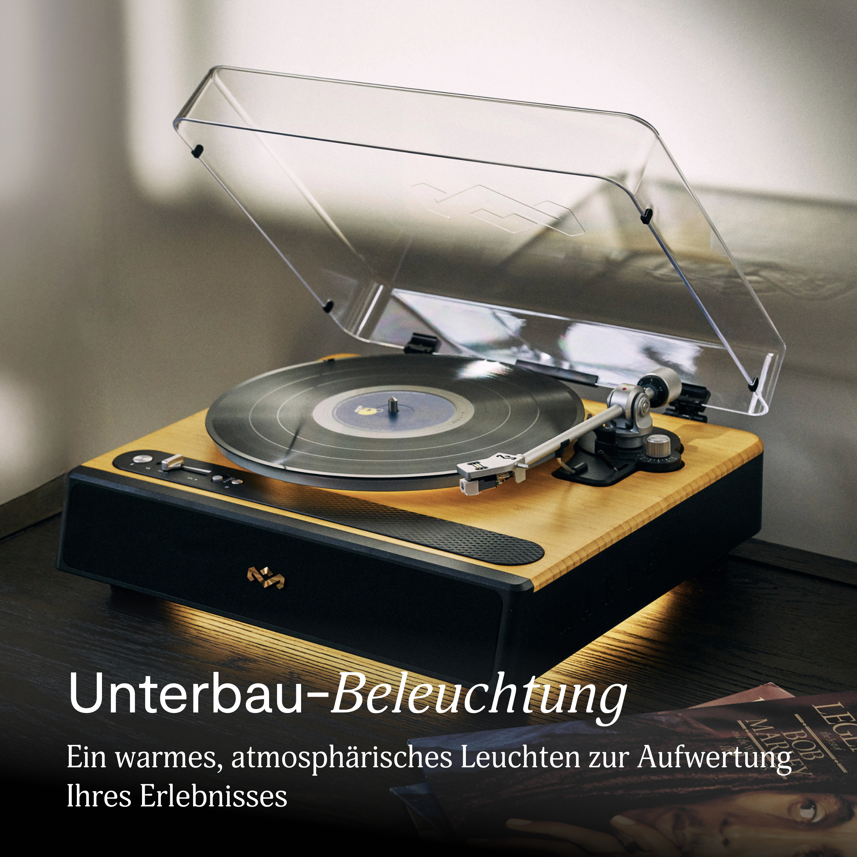 Ein Plattenspieler mit transparentem Deckel auf Holzsockel. Das Bild hat eine warme Beleuchtung.