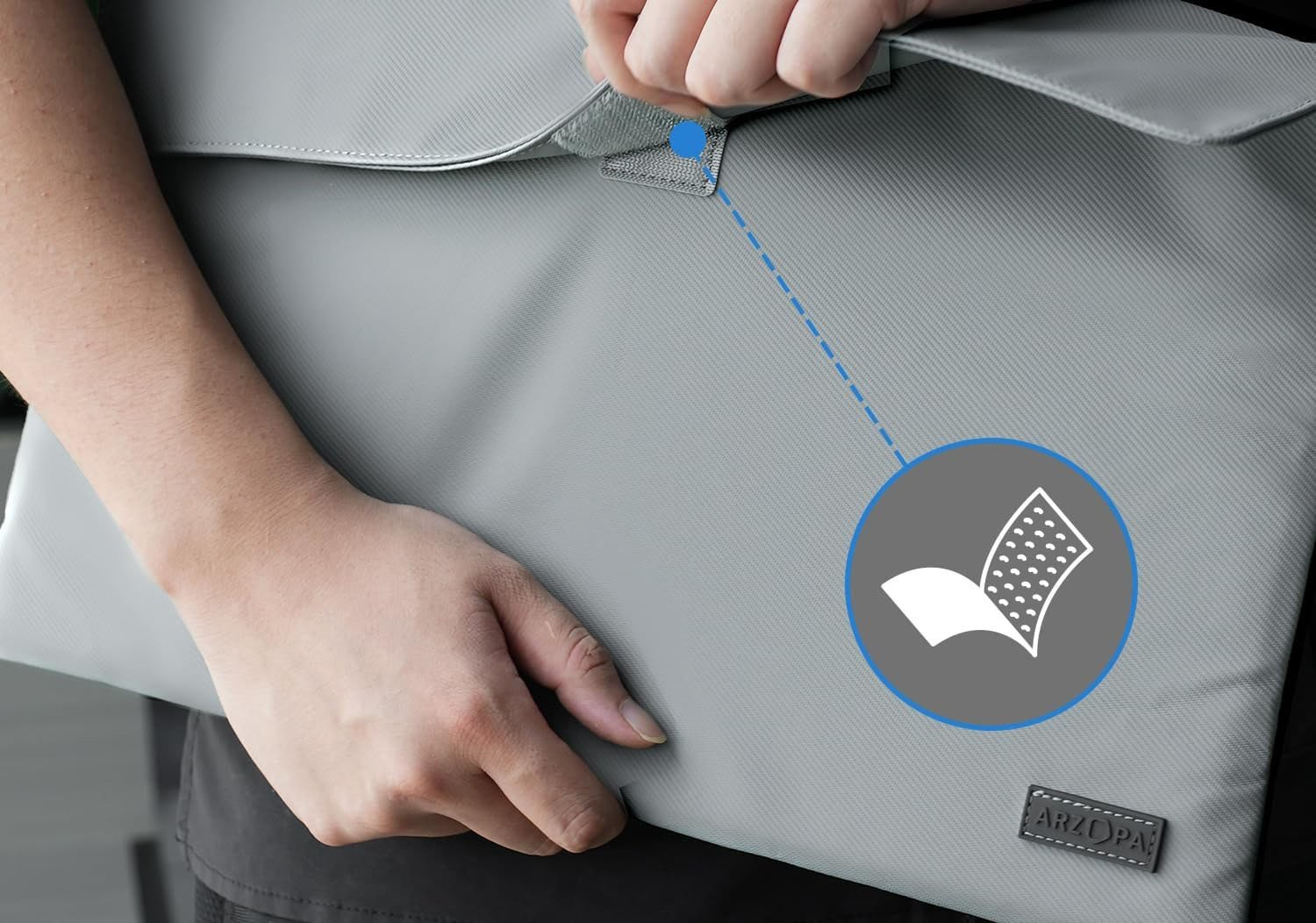 Persona che tiene una custodia grigia per laptop con il marchio 'ARZOPA'. Un diagramma indica un grafico sulla custodia.
