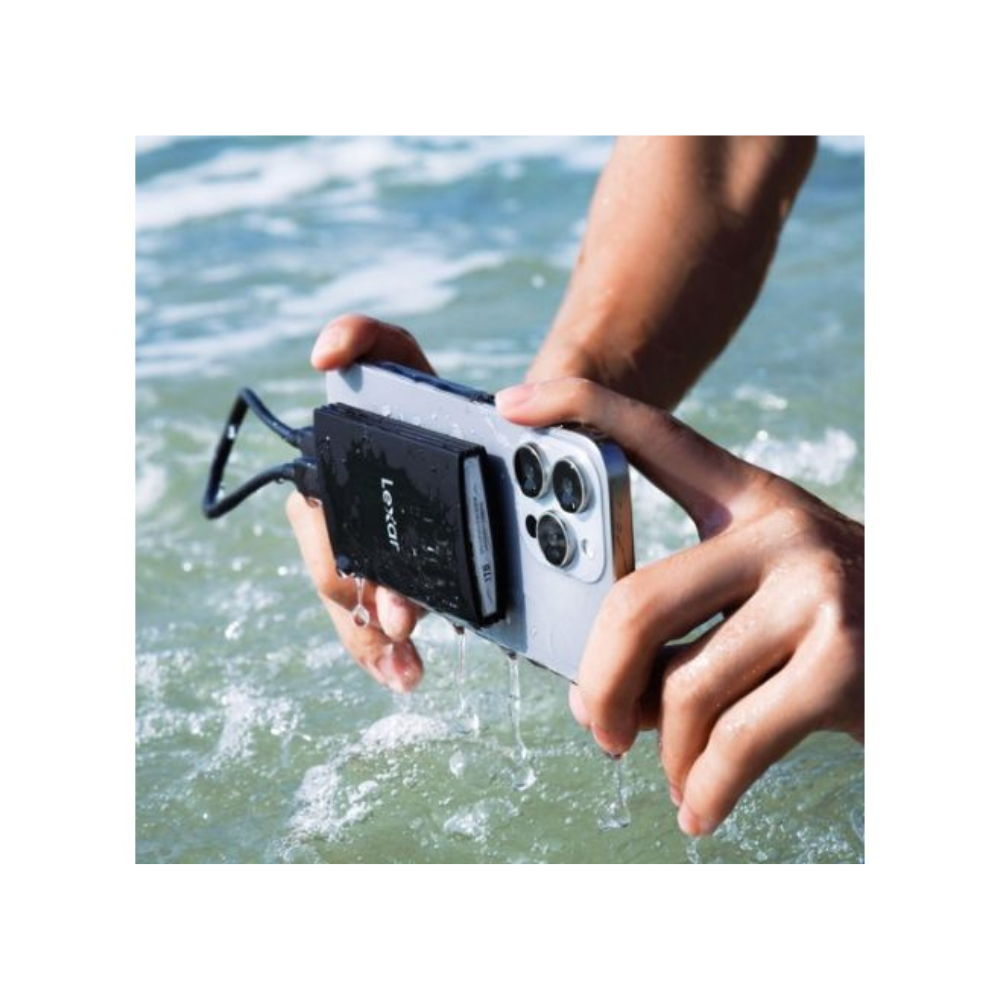 Ręce trzymają smartfona z zewnętrznym dyskiem twardym Lexar, zanurzonym w wodzie. Tło pokazuje wodę.