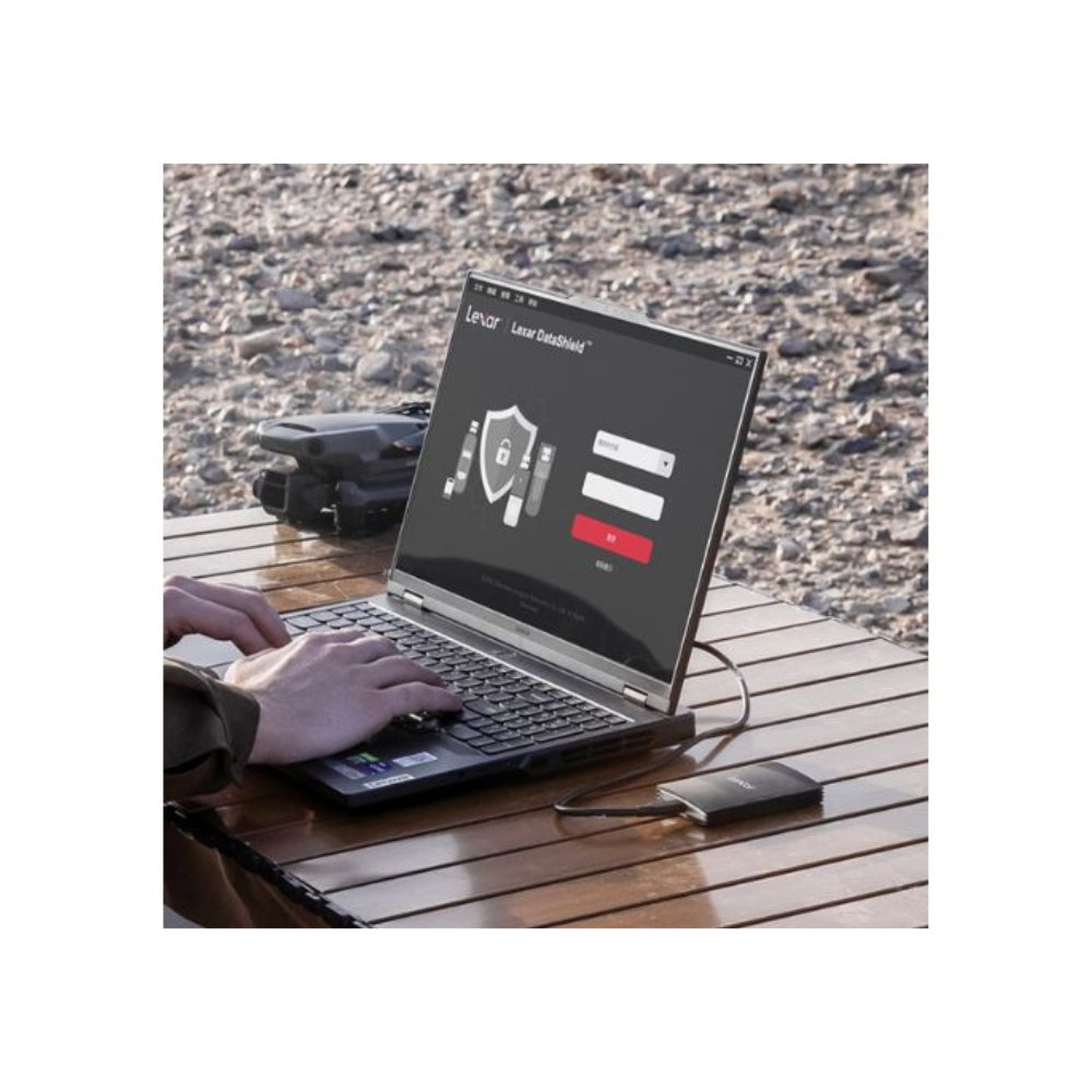 Osoba korzysta z laptopa z oprogramowaniem do ochrony danych. Podłączony jest dysk twardy. W tle na drewnianym stole znajduje się dron.