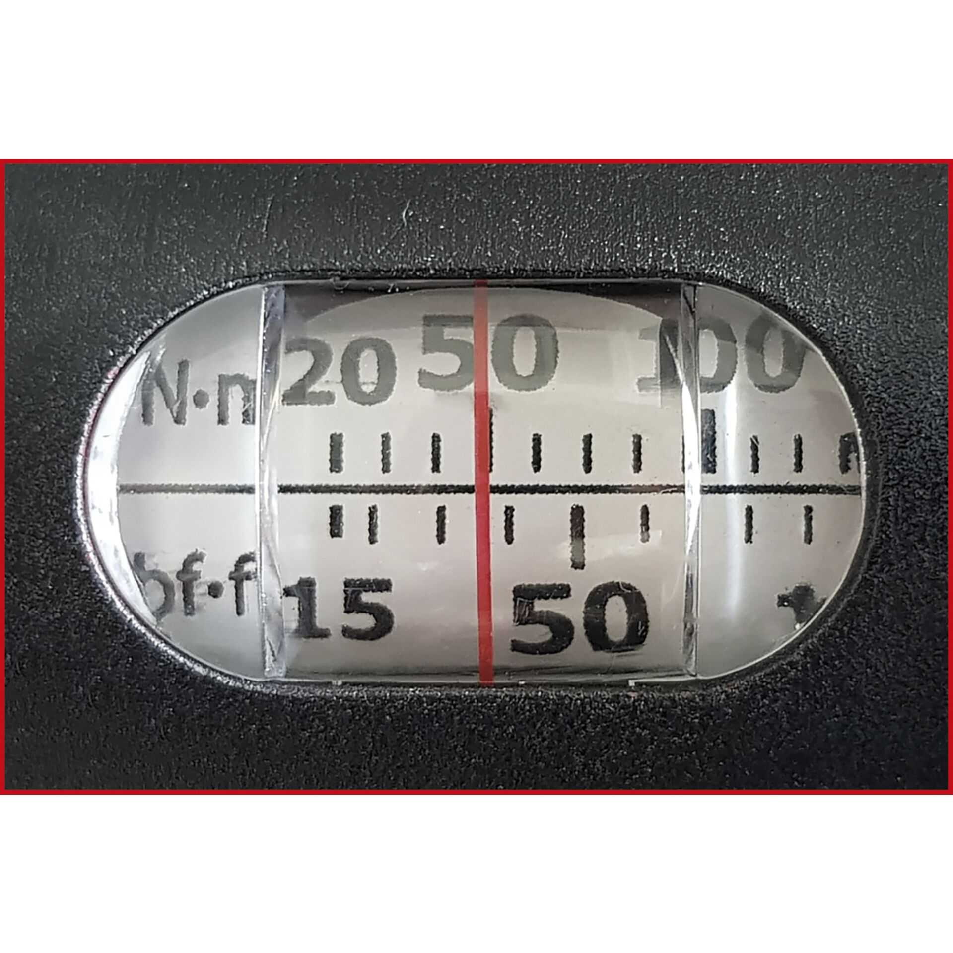 Nahaufnahme eines Messgeräts. Die Zahlen 15, 20, 50 und 100 sind sichtbar. Eine rote Linie geht durch die Mitte. Der Hintergrund ist schwarz.