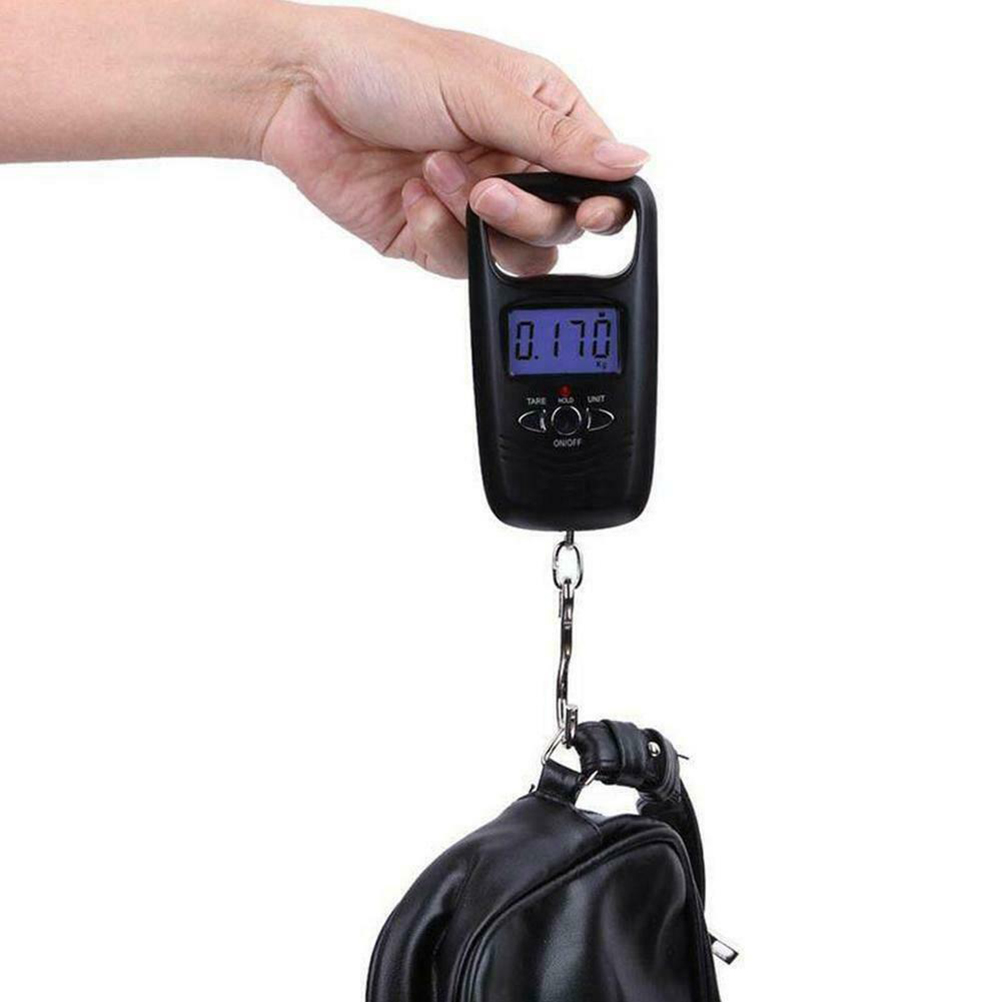 Eine Hand hält eine schwarze digitale Gepäckwaage, die 0,170 kg anzeigt. Eine schwarze Tasche hängt an der Waage.