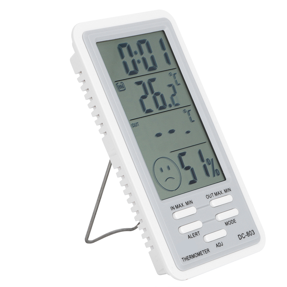 Ein weißes digitales Thermometer zeigt Zeit, Temperatur (26,2 °C) und Luftfeuchtigkeit (51 %) an. Tasten sind ALARM und MODUS. Ein trauriges Smiley-Symbol.