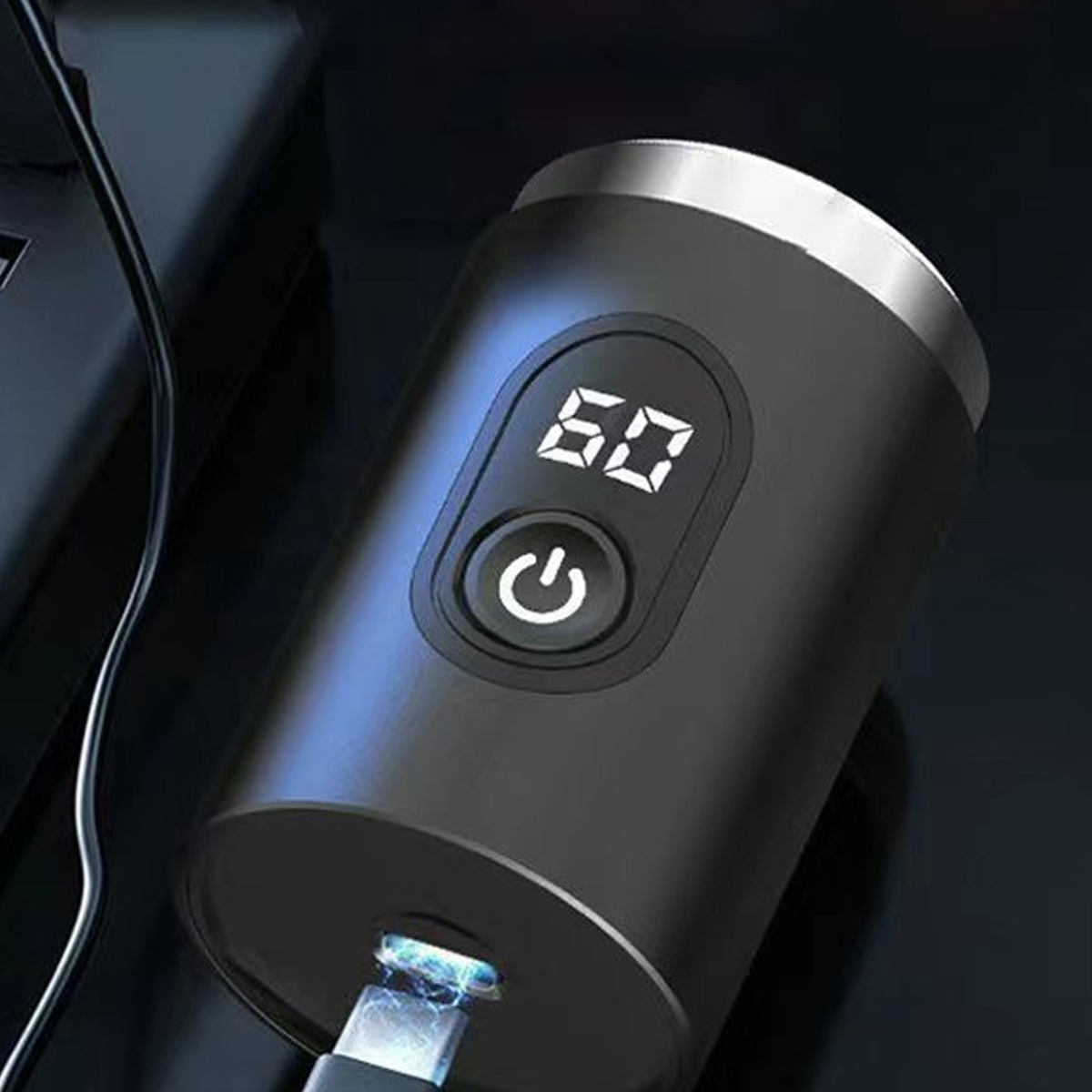 Ein schwarzes Gerät mit Digitalanzeige 60 und Ein-/Aus-Taste. Ein Ladekabel ist unten eingesteckt.