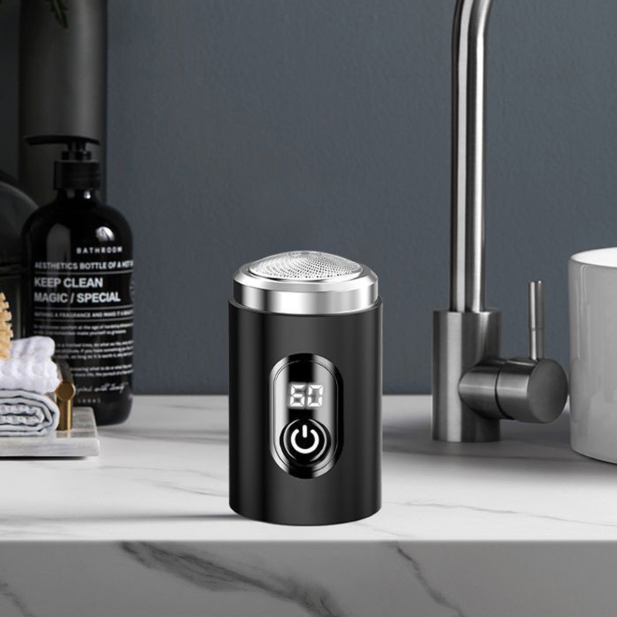 Ein schwarzer Elektrorasierer mit Digitalanzeige und Ein-Aus-Taste steht auf einer Marmorarbeitsplatte. Im Hintergrund befinden sich ein Wasserhahn und eine Flasche.