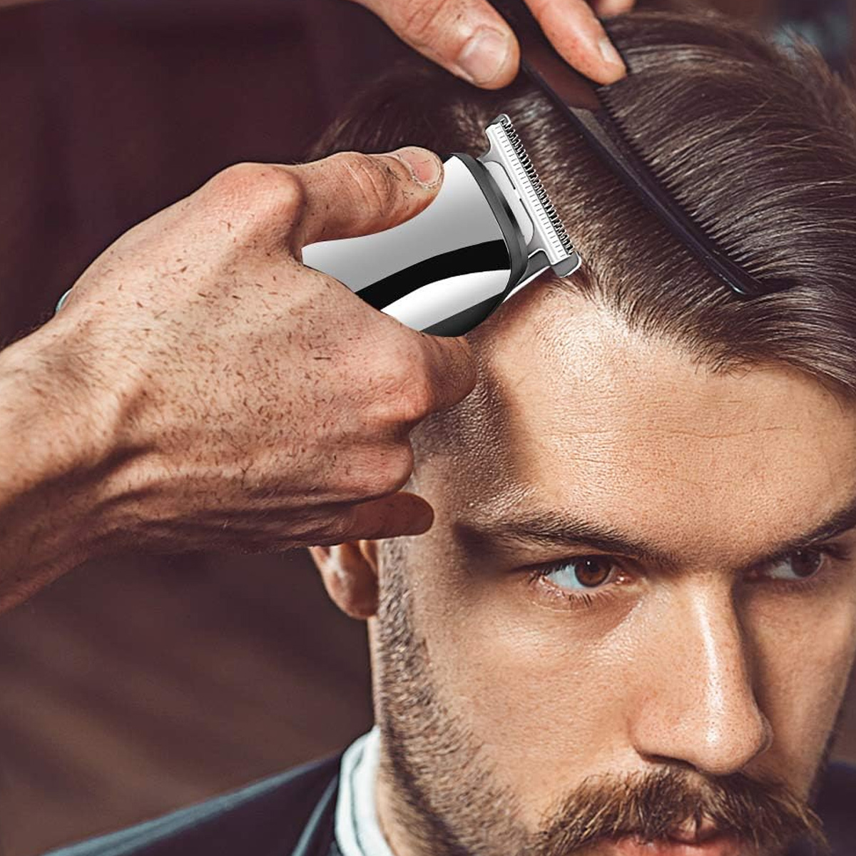 Ein Friseur verwendet einen Haarschneider und einen Kamm auf dem Haar eines Mannes, wobei er sich auf den Oberkopf konzentriert. Der Mann wirkt konzentriert.