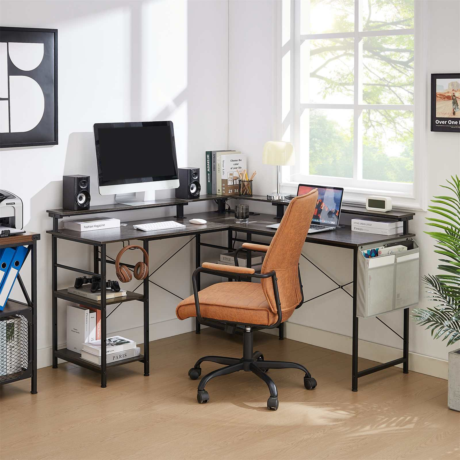 Ein moderner Bürotisch mit Computer, Lautsprechern, Büchern und einem braunen Ledersessel. Im Hintergrund ist ein Fenster.