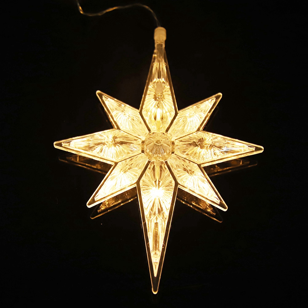 Ein leuchtender sternförmiger Weihnachtsbaumschmuck. Er ist klar mit einem gelben Licht im Inneren. Der Hintergrund ist schwarz und spiegelt den Stern wider.