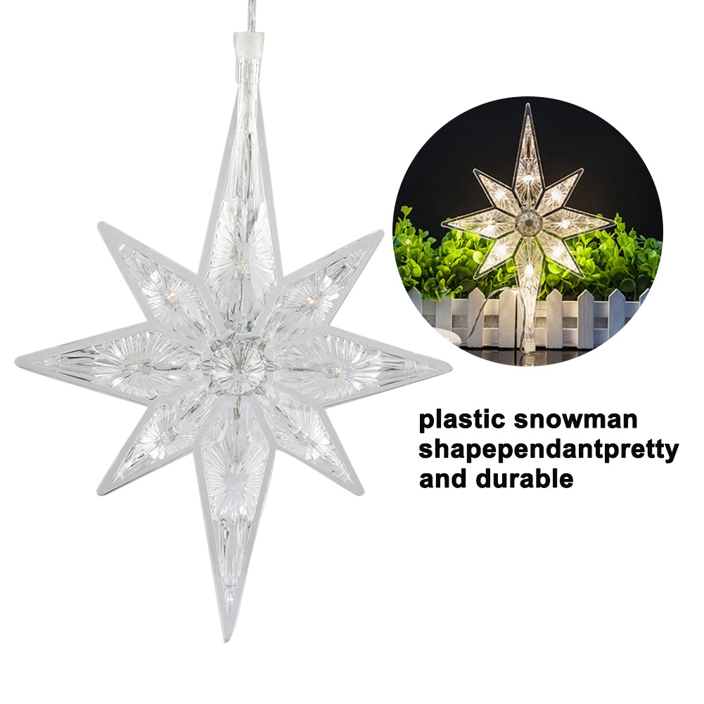 Ein klarer, sternförmiger Weihnachtsbaumschmuck aus Kunststoff hängt. Eine kleinere Version wird in einem Kreis gezeigt, beleuchtet, mit einem weißen Zaun dahinter.