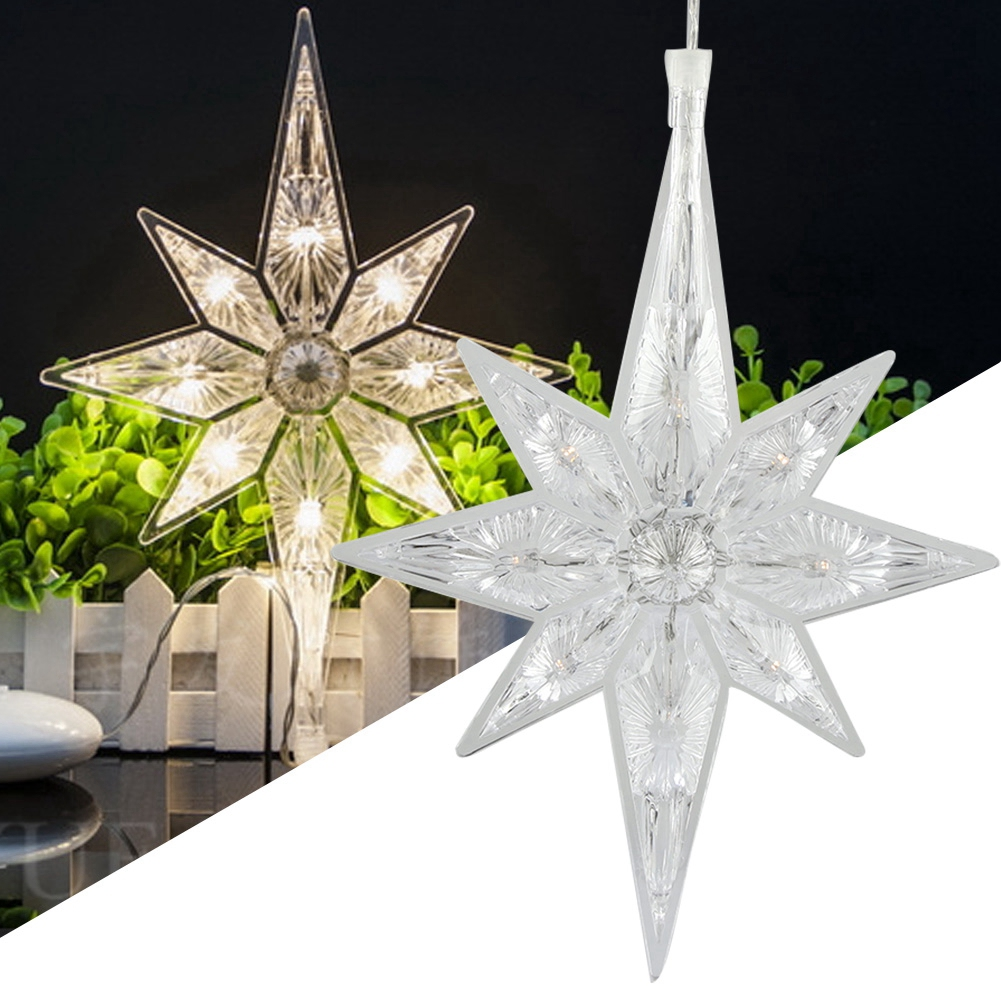 Zwei klare, sternförmige Weihnachtslichter. Eines leuchtet, das andere nicht. Der Hintergrund zeigt einen weißen Zaun und Pflanzen.
