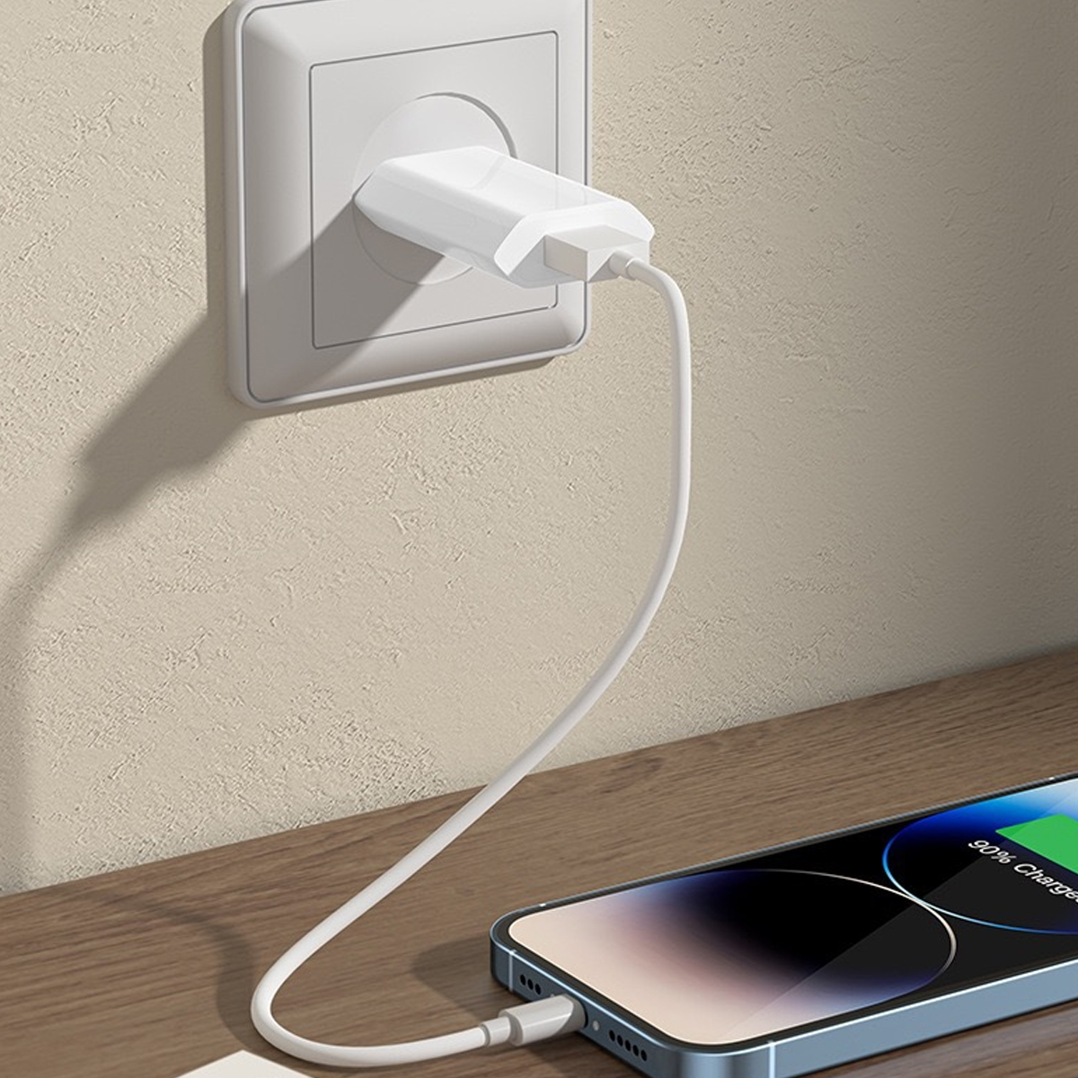 Ein Telefon, das mit einem weißen Kabel und Ladegerät aufgeladen wird. Das Telefon liegt auf einer Holzoberfläche. Das Ladegerät befindet sich in einer Steckdose.