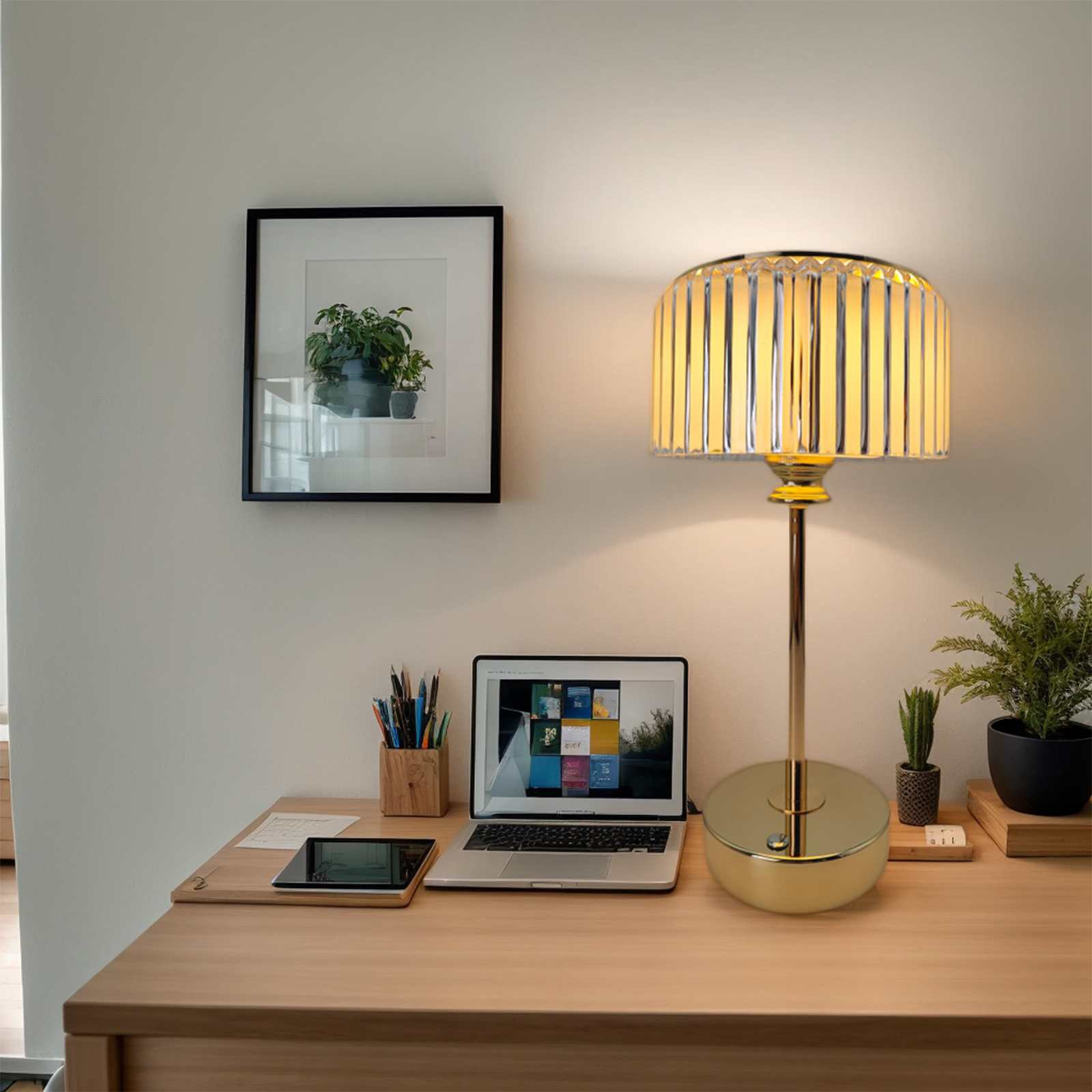 Ein Schreibtisch mit Laptop, Lampe und gerahmter Kunst. Ein Tablet und Stifthalter sind ebenfalls sichtbar.