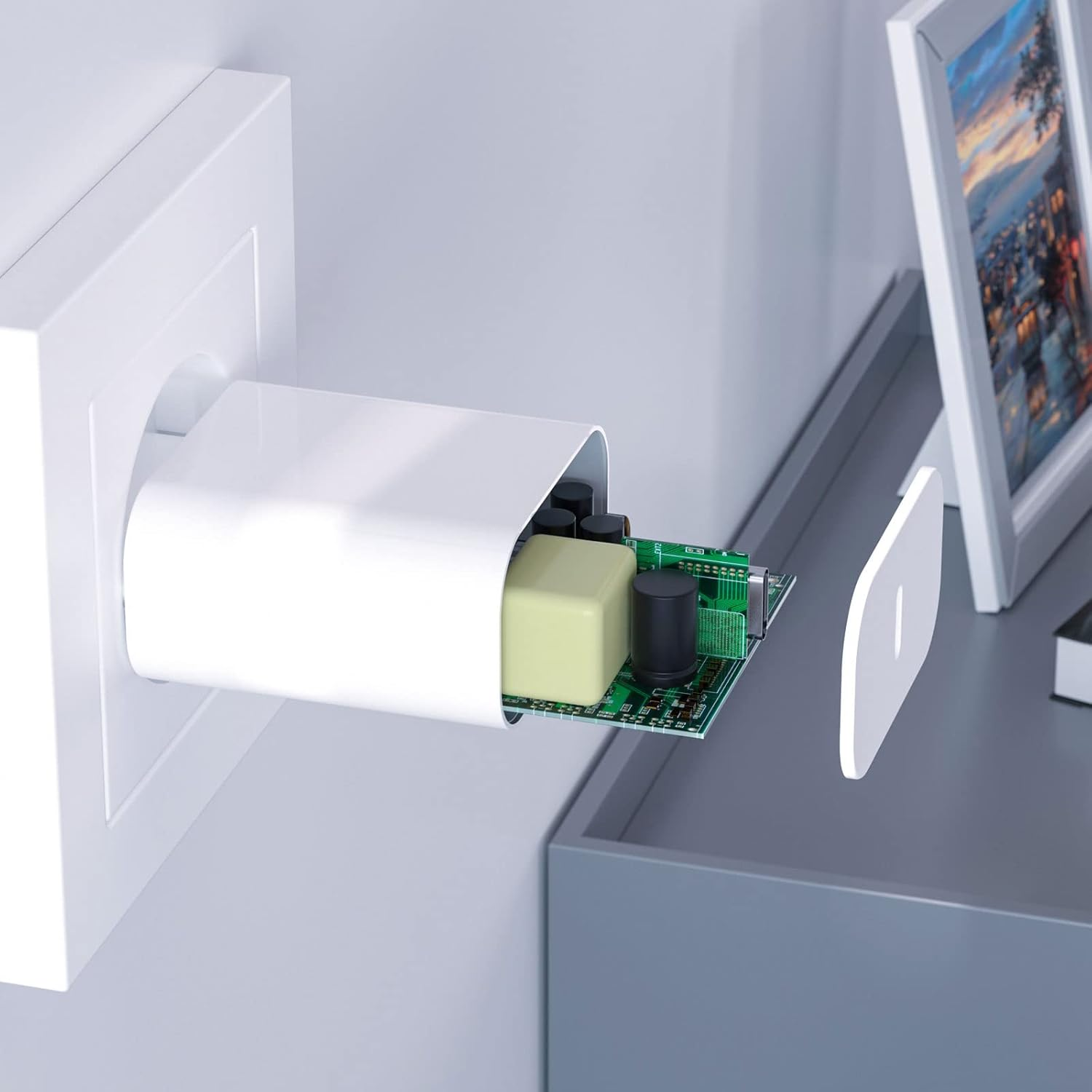 Weiße Steckdose mit zerlegtem weißen Gerät, das die interne Elektronik freilegt. Ein Bilderrahmen steht auf einer grauen Oberfläche.
