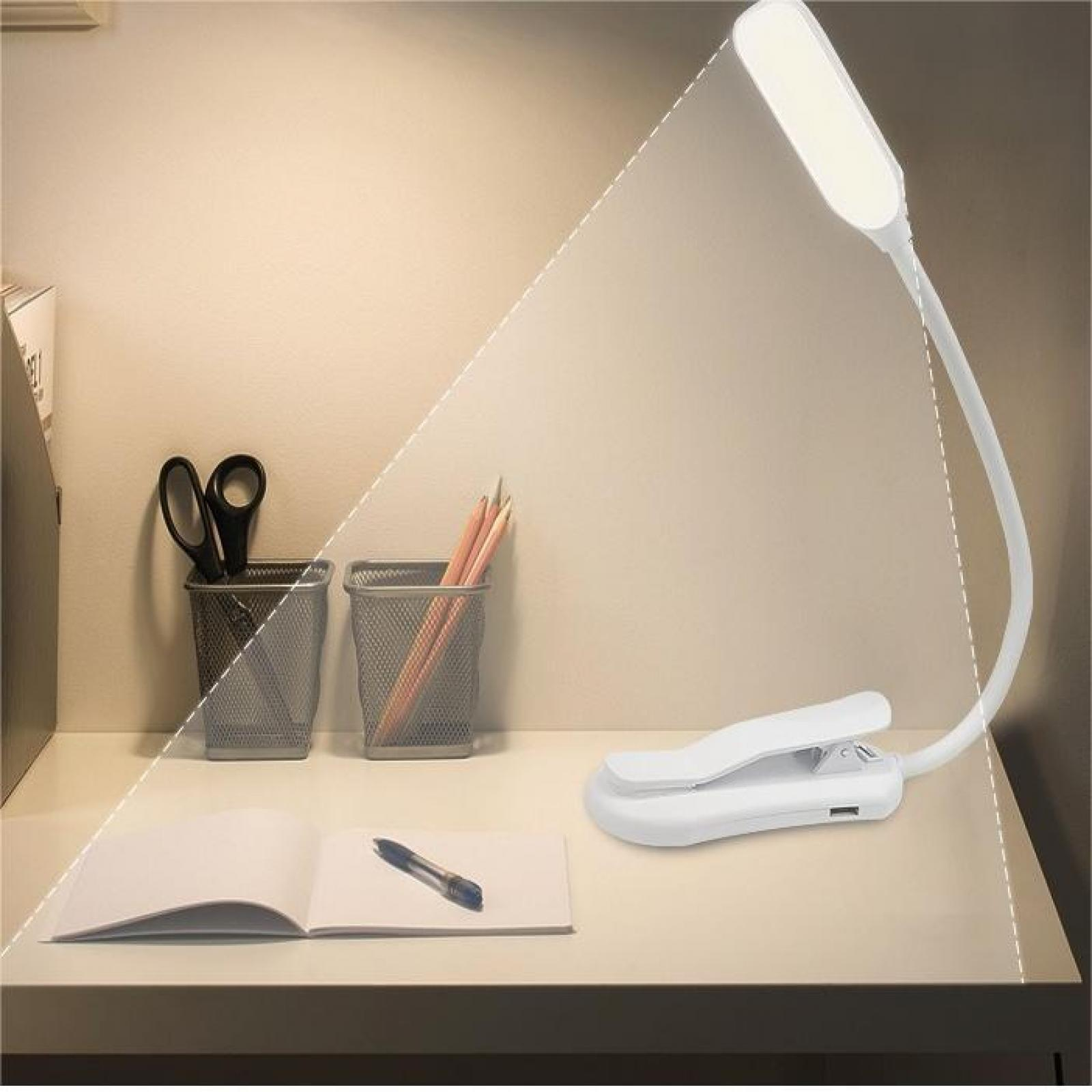 Eine weiße Schreibtischlampe beleuchtet einen Schreibtisch. Auf dem Schreibtisch liegen eine Schere, Bleistifte, ein Notizbuch und ein Stift.
