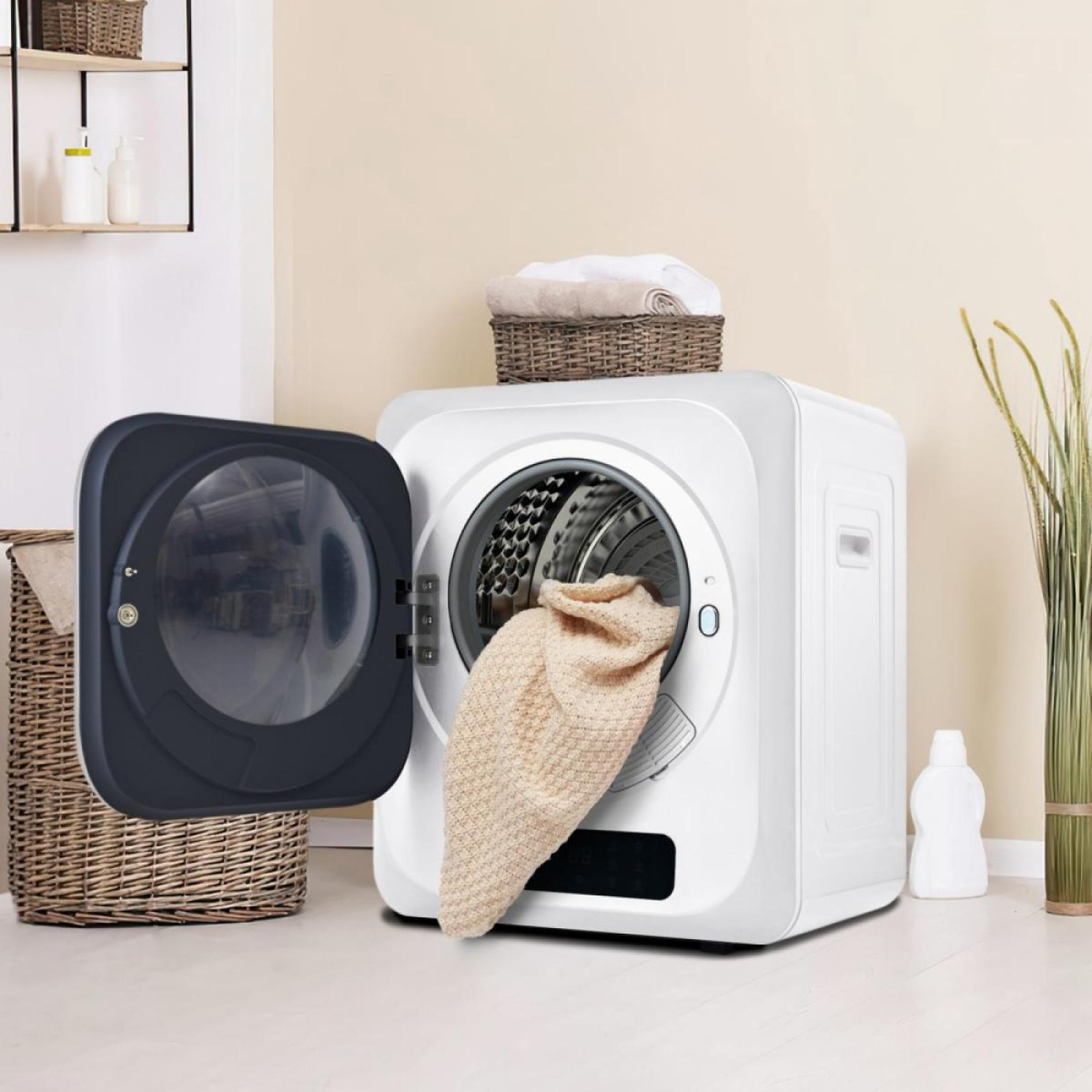 Eine weiße Waschmaschine mit offener Tür, eine beige Decke kommt heraus. Oben steht ein Korb mit Handtüchern.