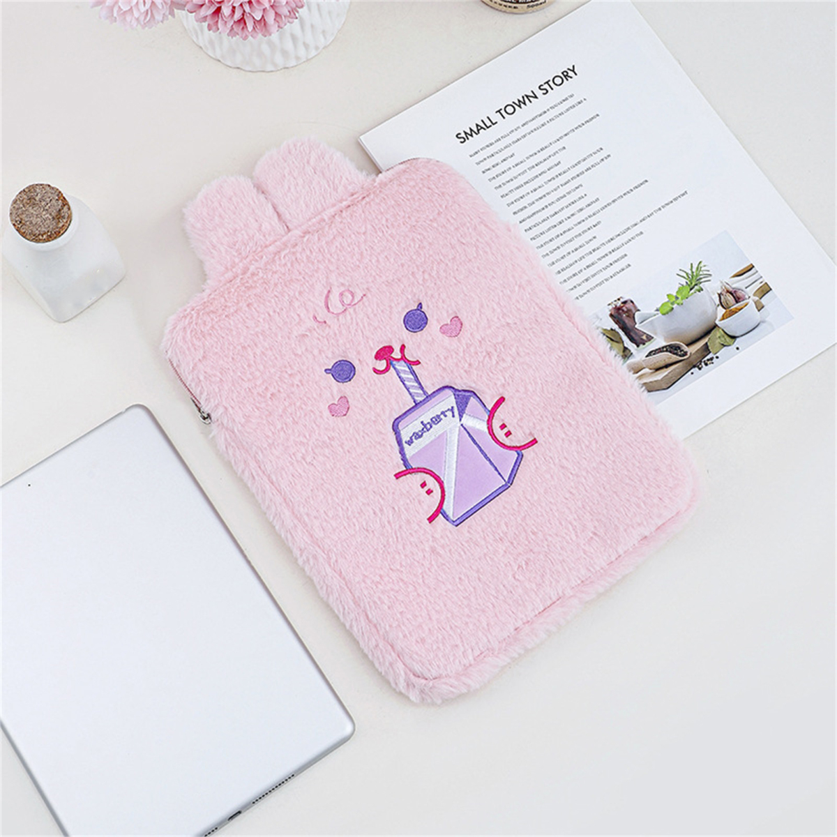 Rosa flauschige Hülle mit Hasenohren und einer Getränkeillustration. Ein Tablet, ein Buch und ein kleines Glas sind auch sichtbar.
